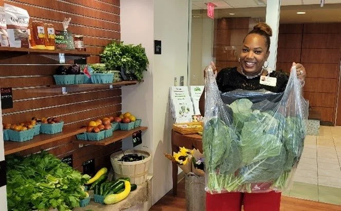 Person smiling with bag of leafy produce at The Farm
