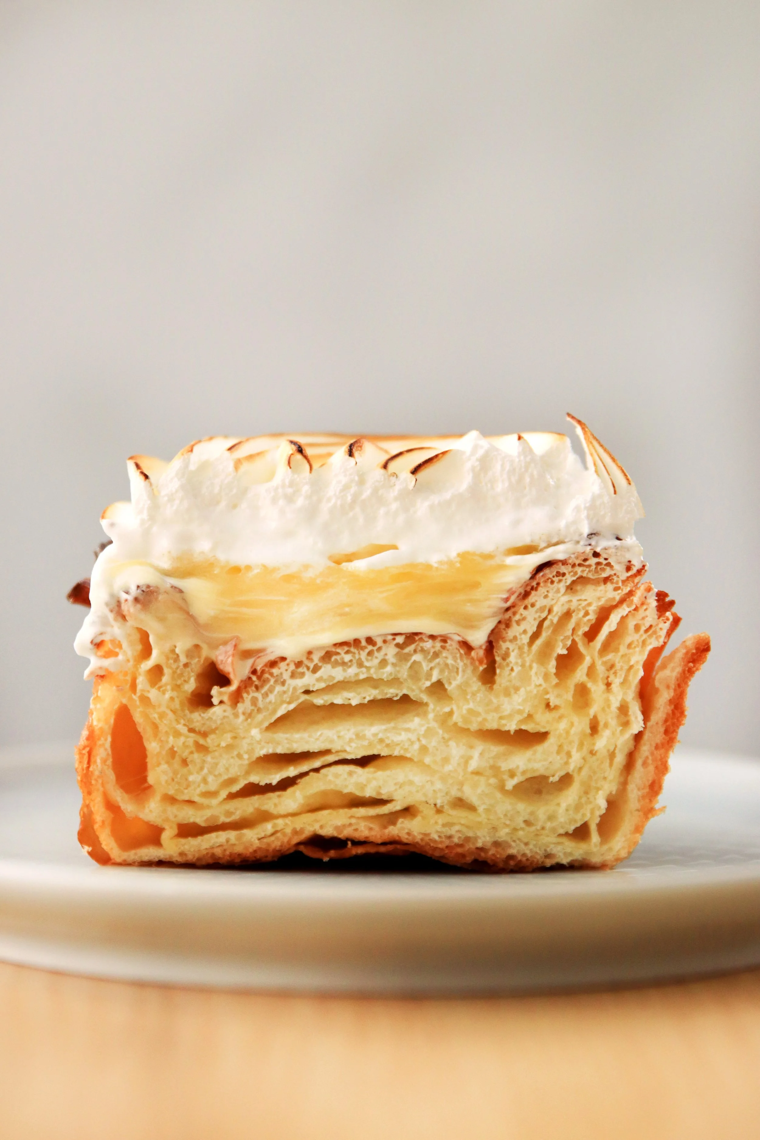 Postre con hojaldre, crema y merengue en un plato blanco.