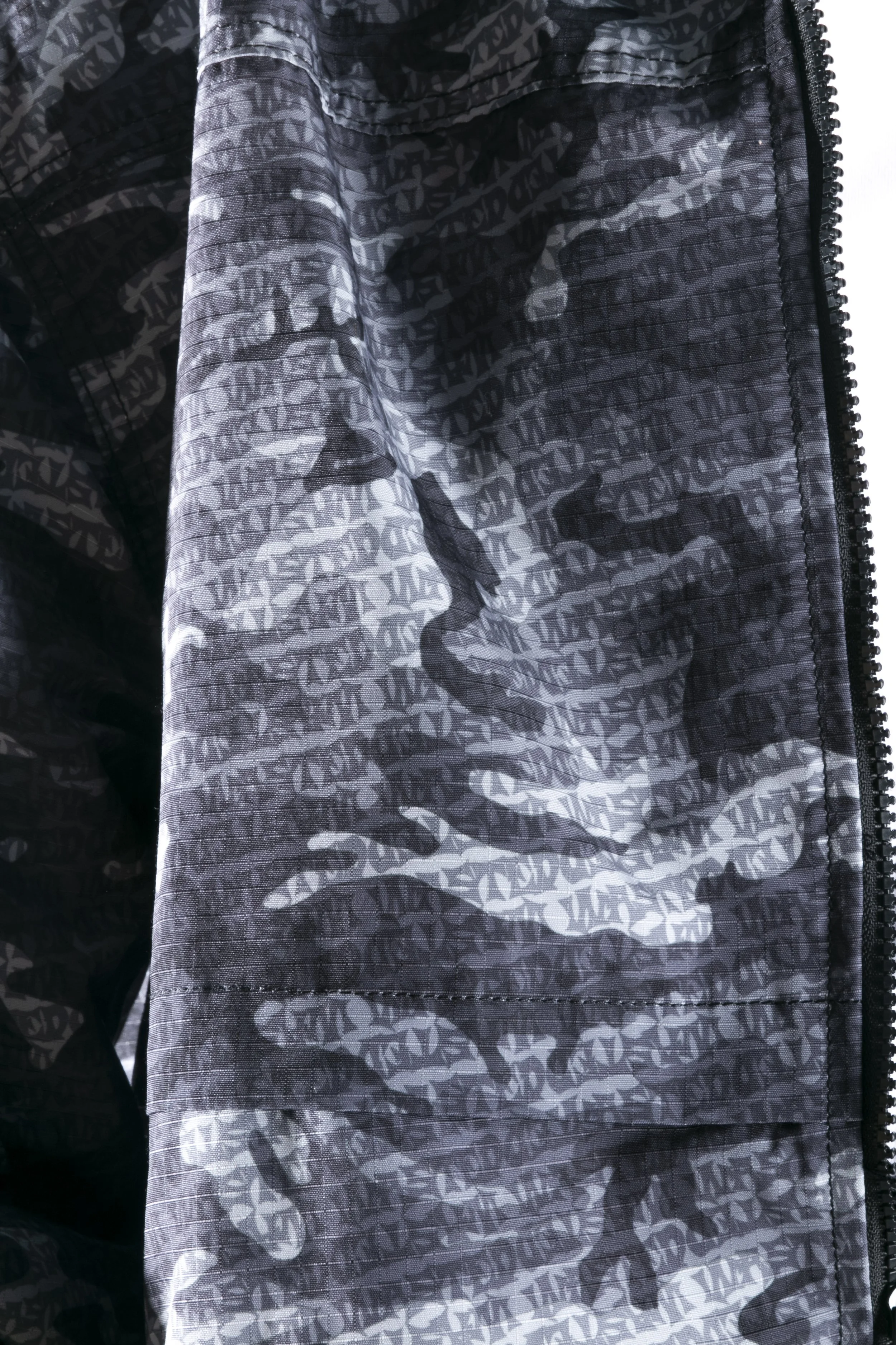 Veste noire avec un motif en blanc et gris, incluant une image de visage d'une femme et un motif en forme de logo.