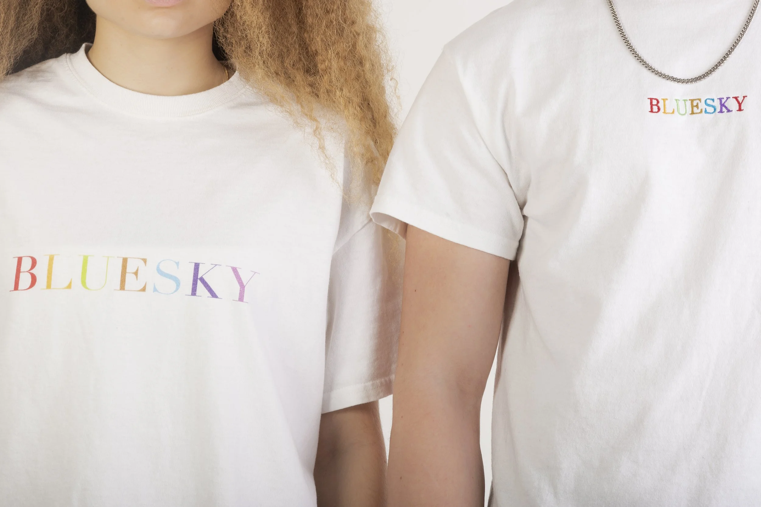 Deux personnes portant des t-shirts blancs avec le mot «BLUESKY» écrit en lettres de différentes couleurs.