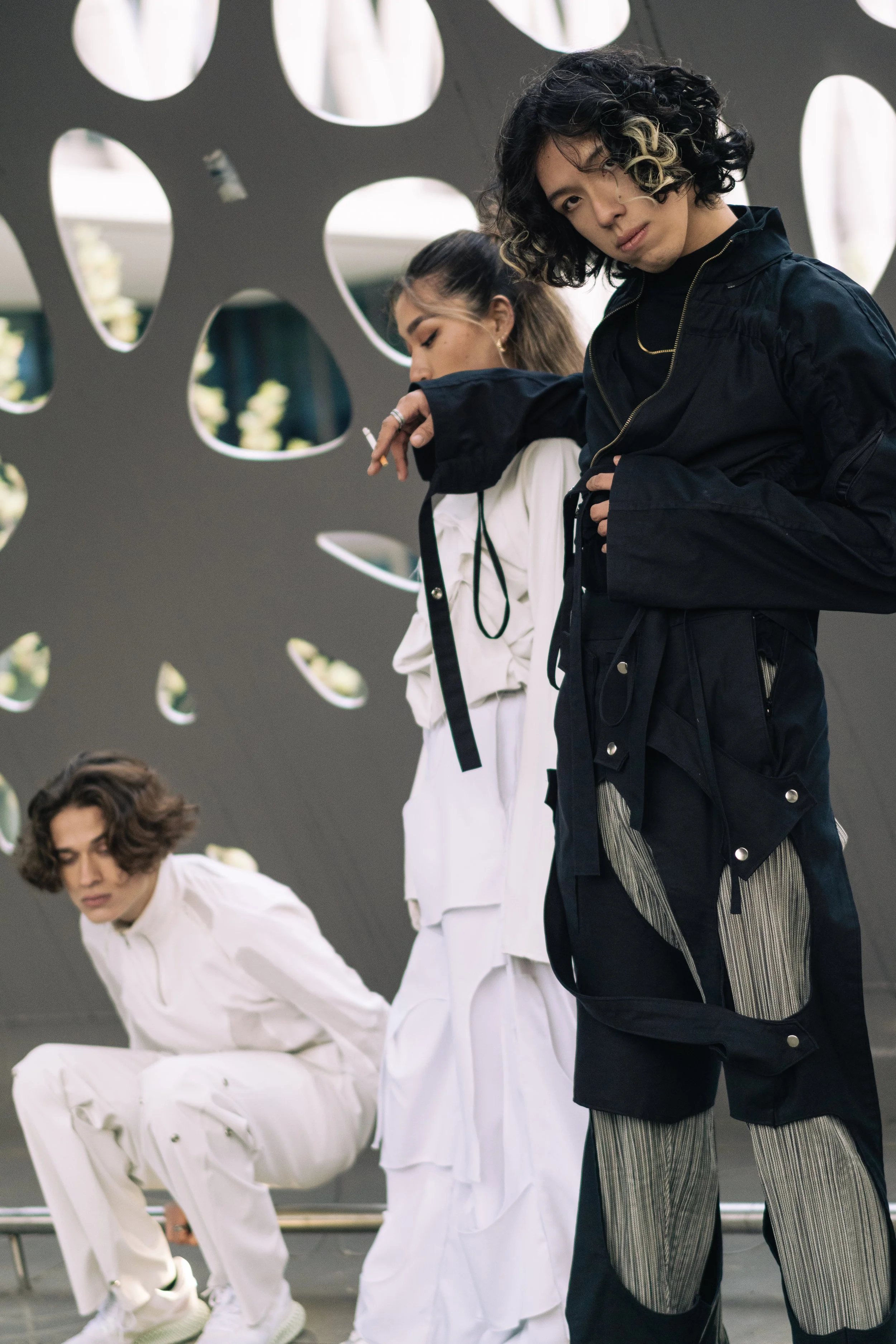 Trois jeunes personnes posant devant une structure en forme de bulles ou de trous.