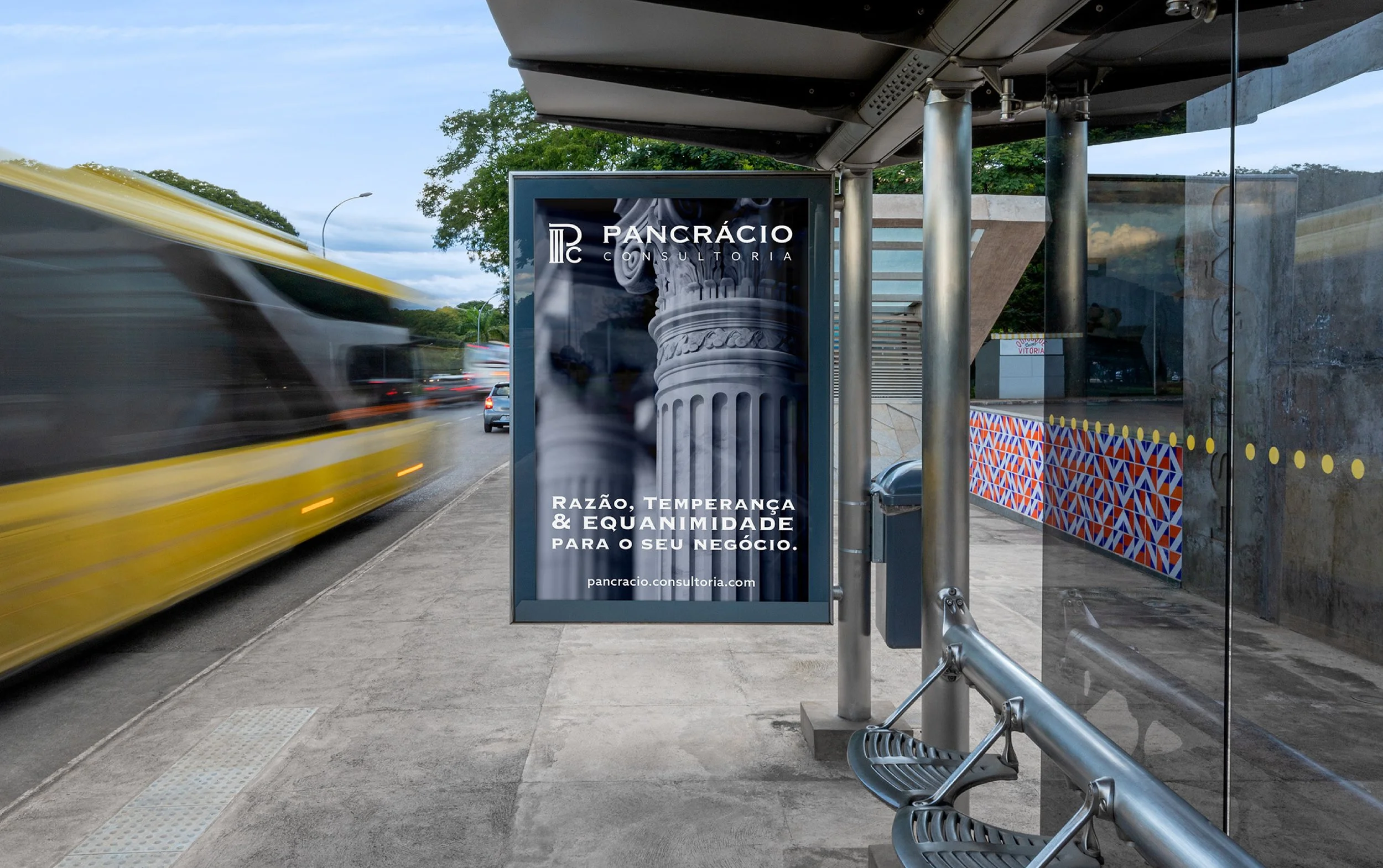 Bus stop shelter with an advertisement for Pancracio Consultoria, featuring a Corinthian column capital and text in Portuguese.
