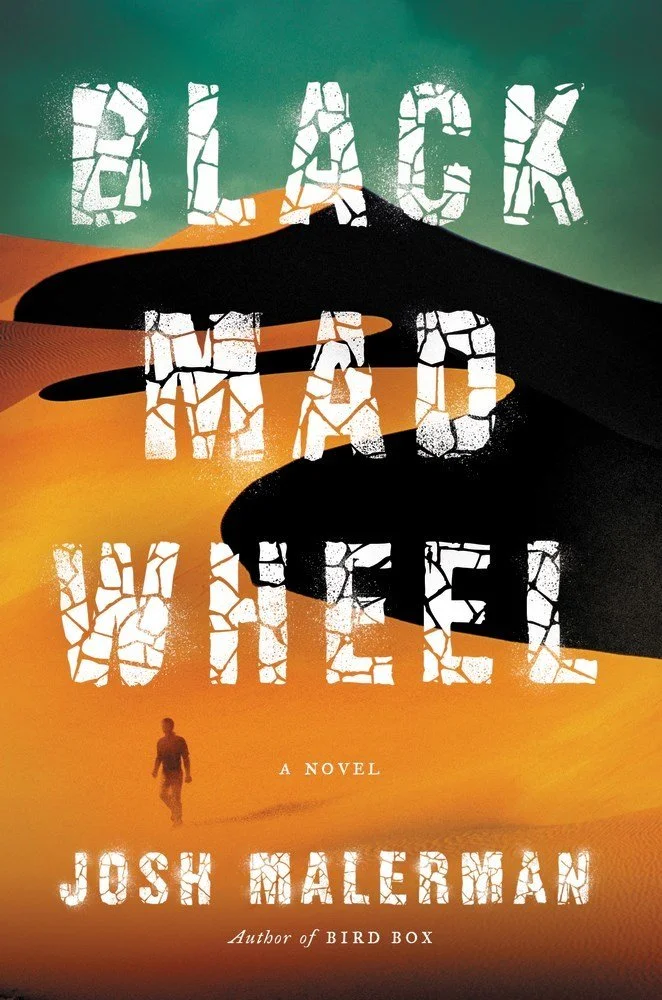 The cover of the novel 'Black Box' by Josh Malerman features a desert landscape with sand dunes in shades of orange and yellow. A person walks alone in the distance, with large black shadows of hands looming over. The title and author's name are writ
