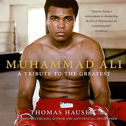 Book cover of "Muhammad Ali: A Tribute to the Greatest" by Thomas Hauser, featuring a shirtless young Muhammad Ali wearing red boxing gloves, sitting and looking directly at the camera.