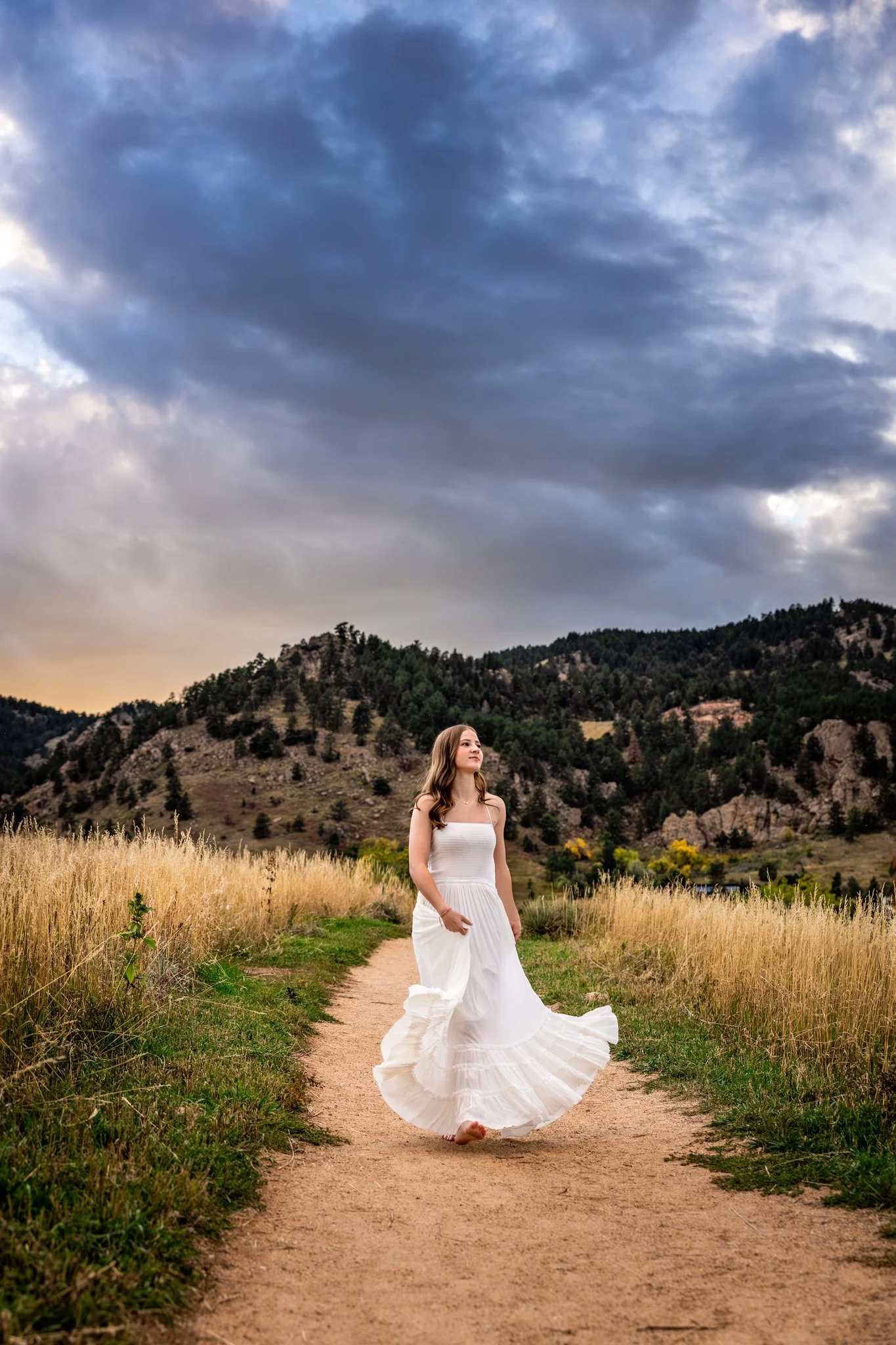 A gorgeous scenic senior portrait with stormy skies and girl in a long white maxi dress taken by Kim Graves Photography