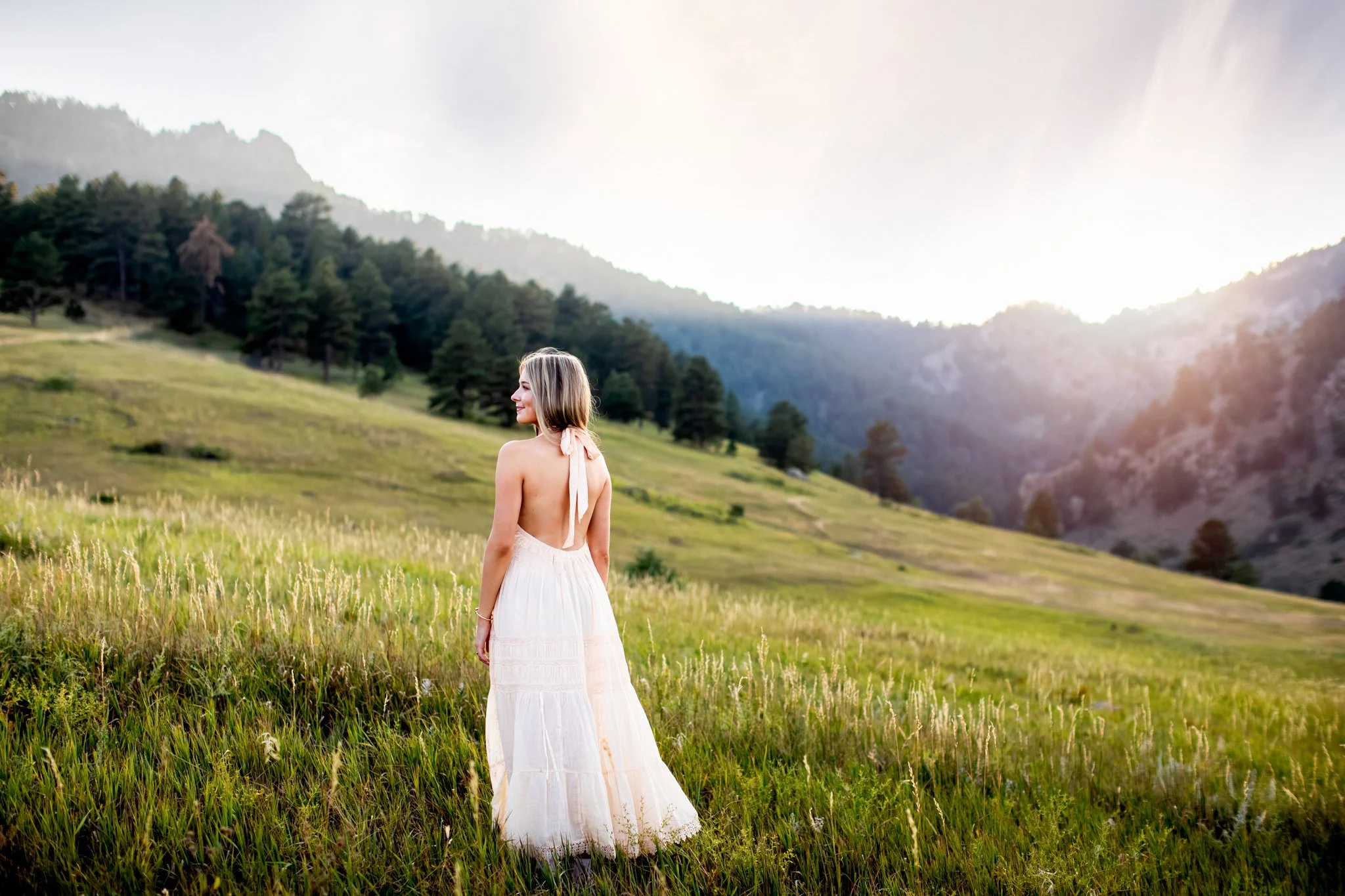 Boulder Senior Photographer captures image of girl standing on a green hill side with the sunsetting