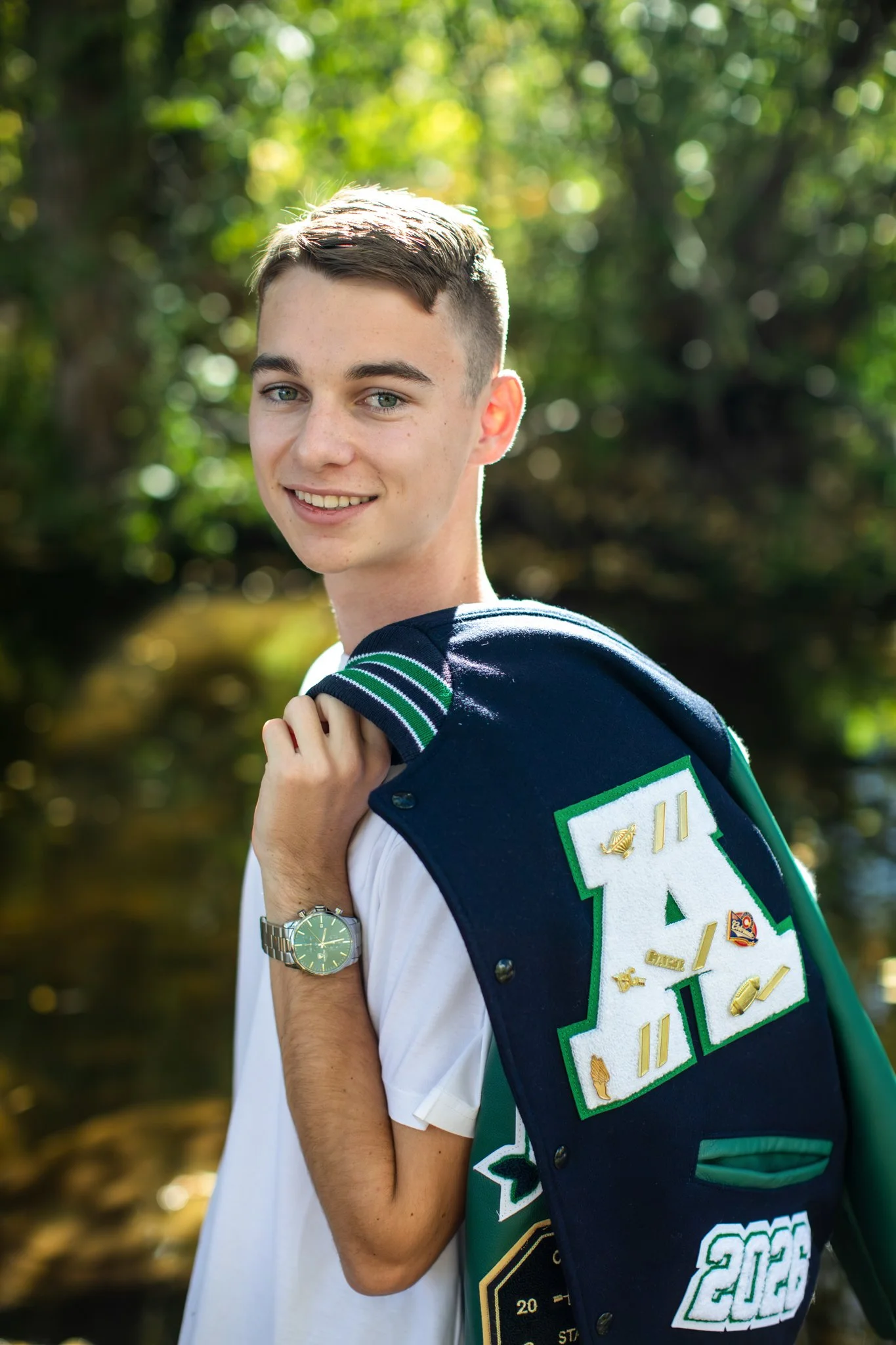 Young high school senior boy holding his letter man jacket over his shoulder.