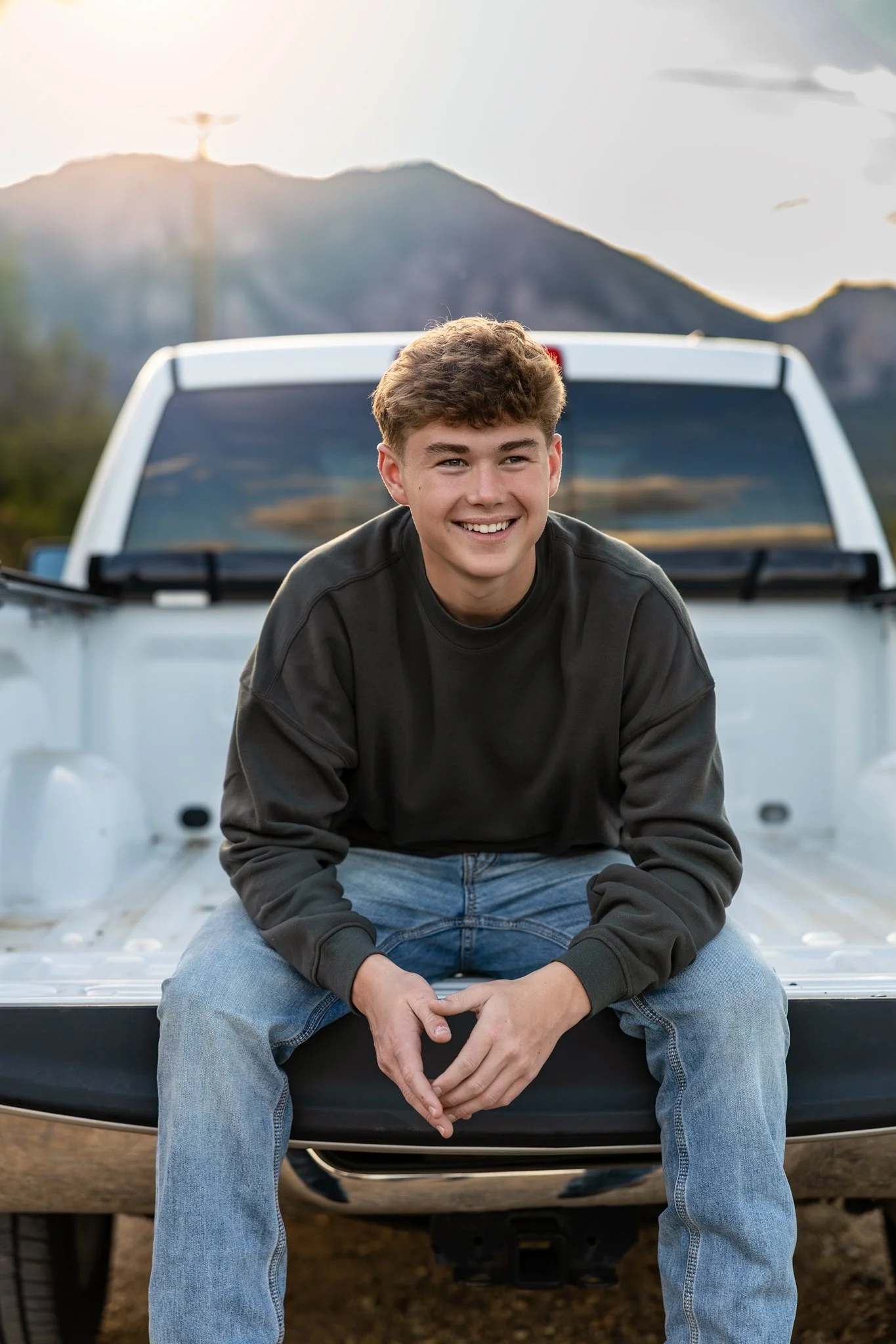 Erie High School Senior boy gets his portrait taken sitting on the flatbed of his white truck.