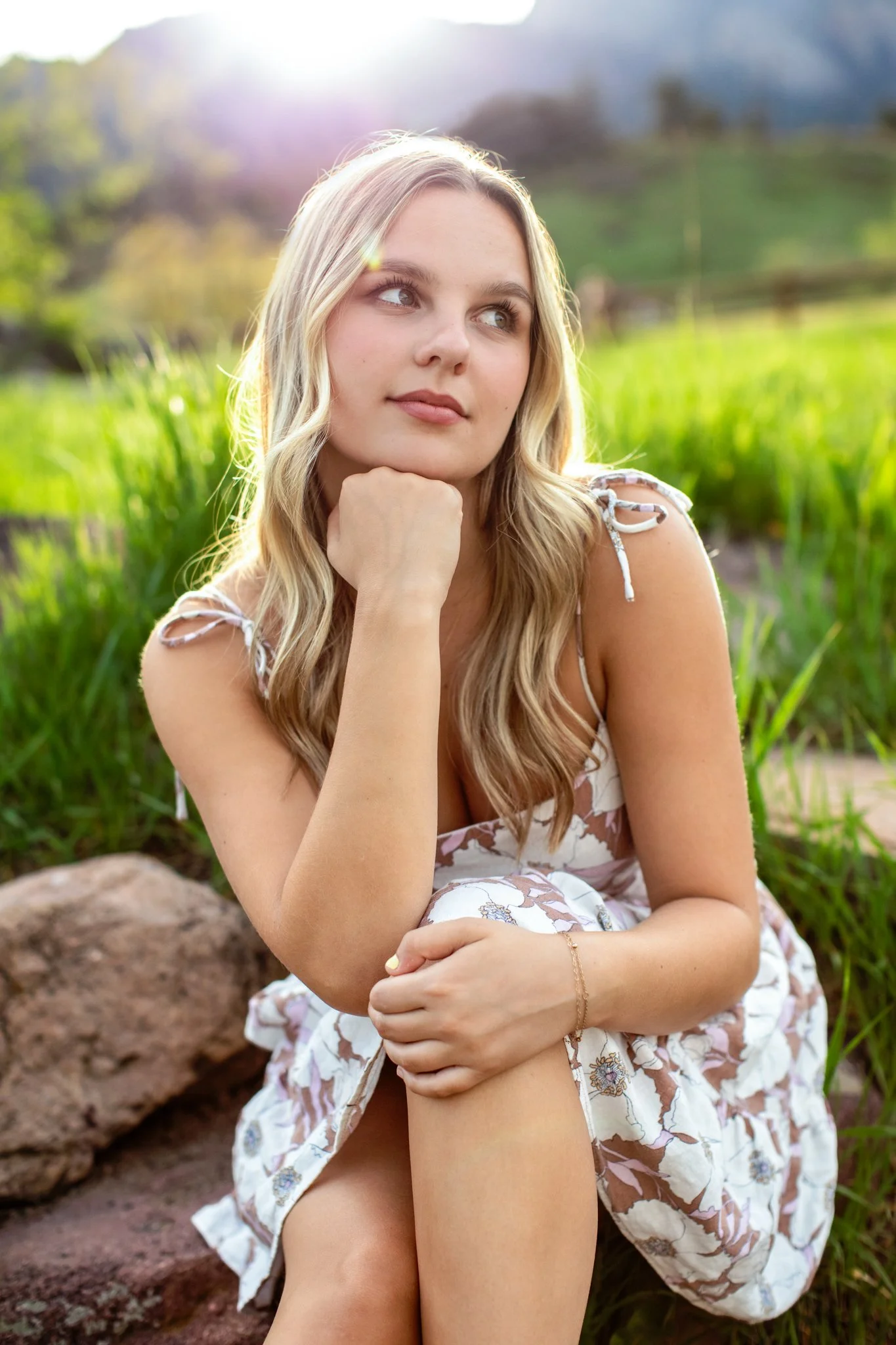 College woman in white dress resting her chin on her hand. Portrait taken by Kim Graves Photography in Boulder, Colorado.