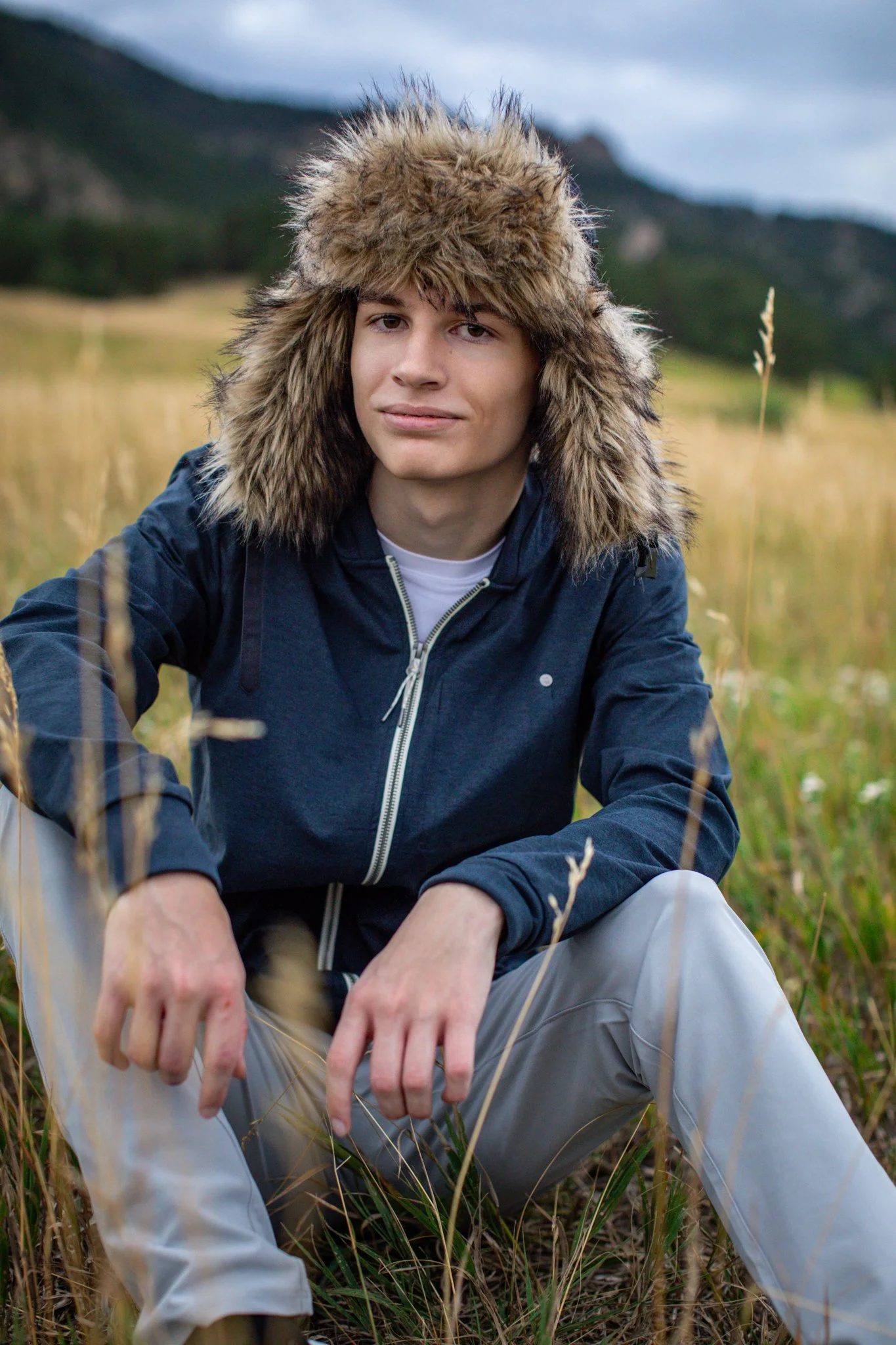Portrait of male senior high school student in navy sweater and fur lined hat.