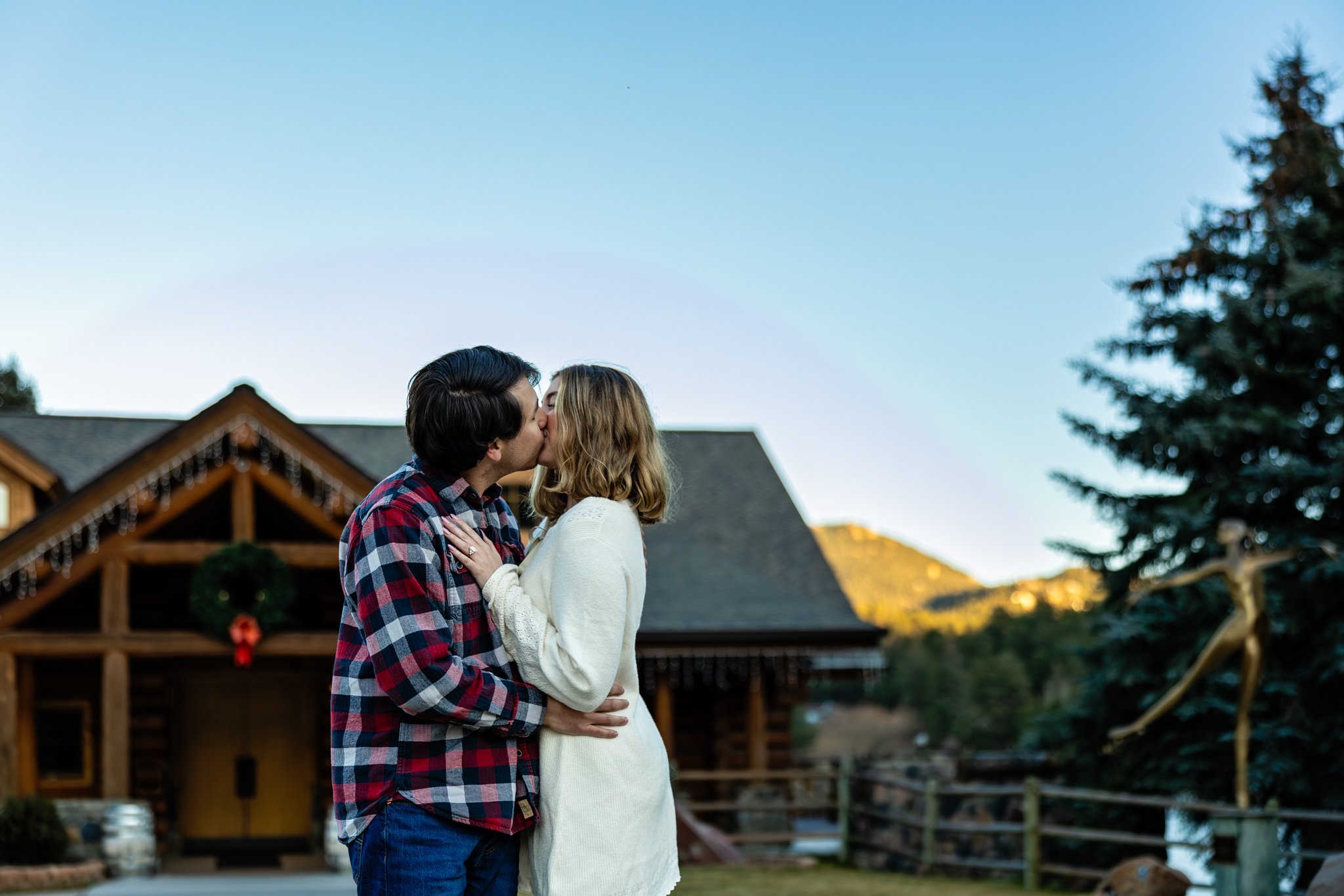 Engagement photo of couple kissing outside the Lake House in Evergreen Colorado.