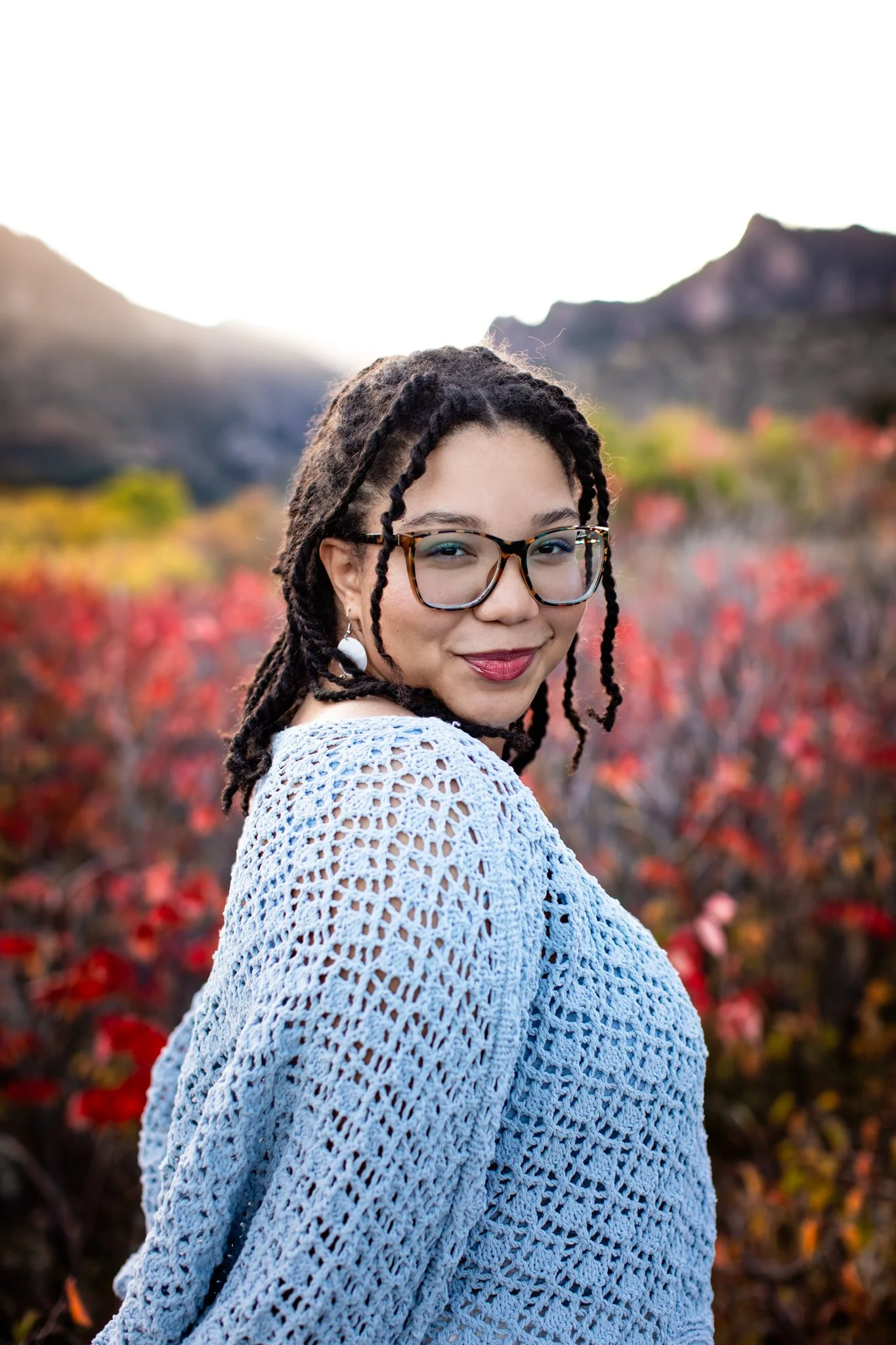 Colorado High School Senior Photographer takes pictures of girl with red lip stick surrounded by a field of red bushes.