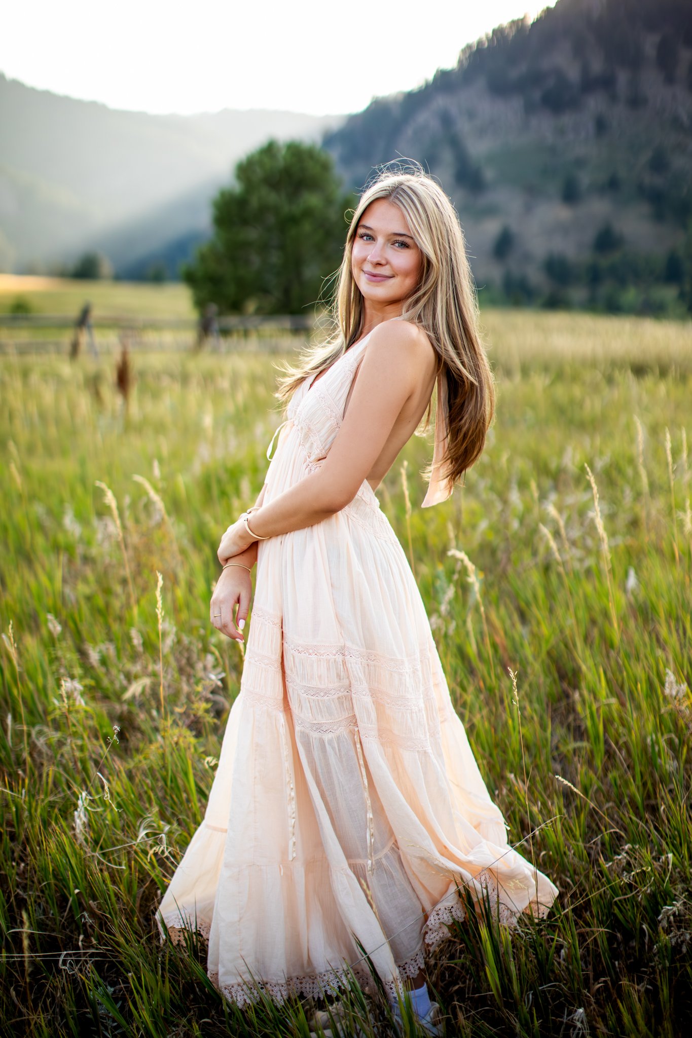Colorado Senior Photographer captures portrait of girl in free people pale pink maxi dress standing a green field.