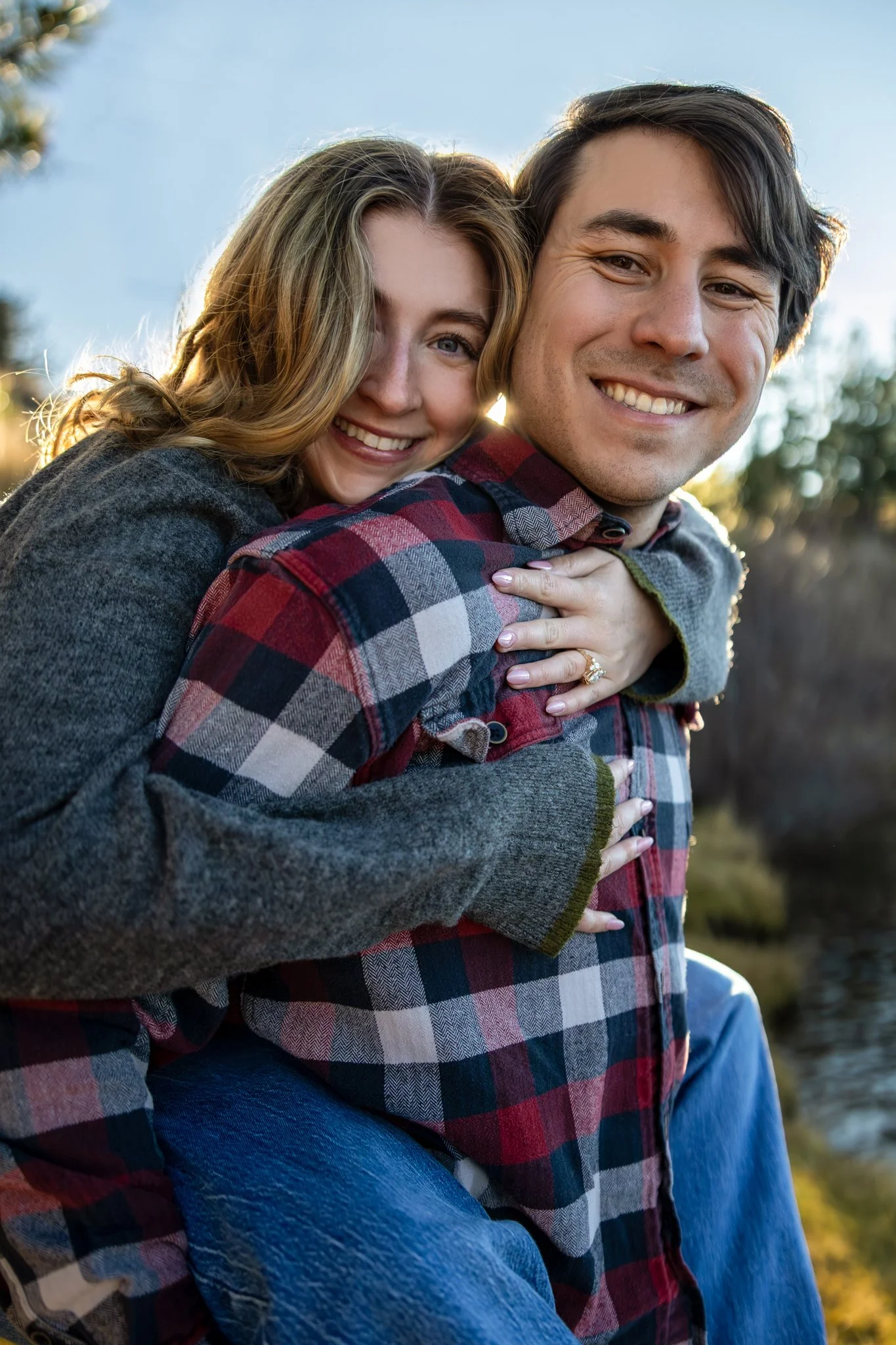 Engagement portraits taken by Kim Graves Photography of a young woman getting a piggy back from her fiancé. 