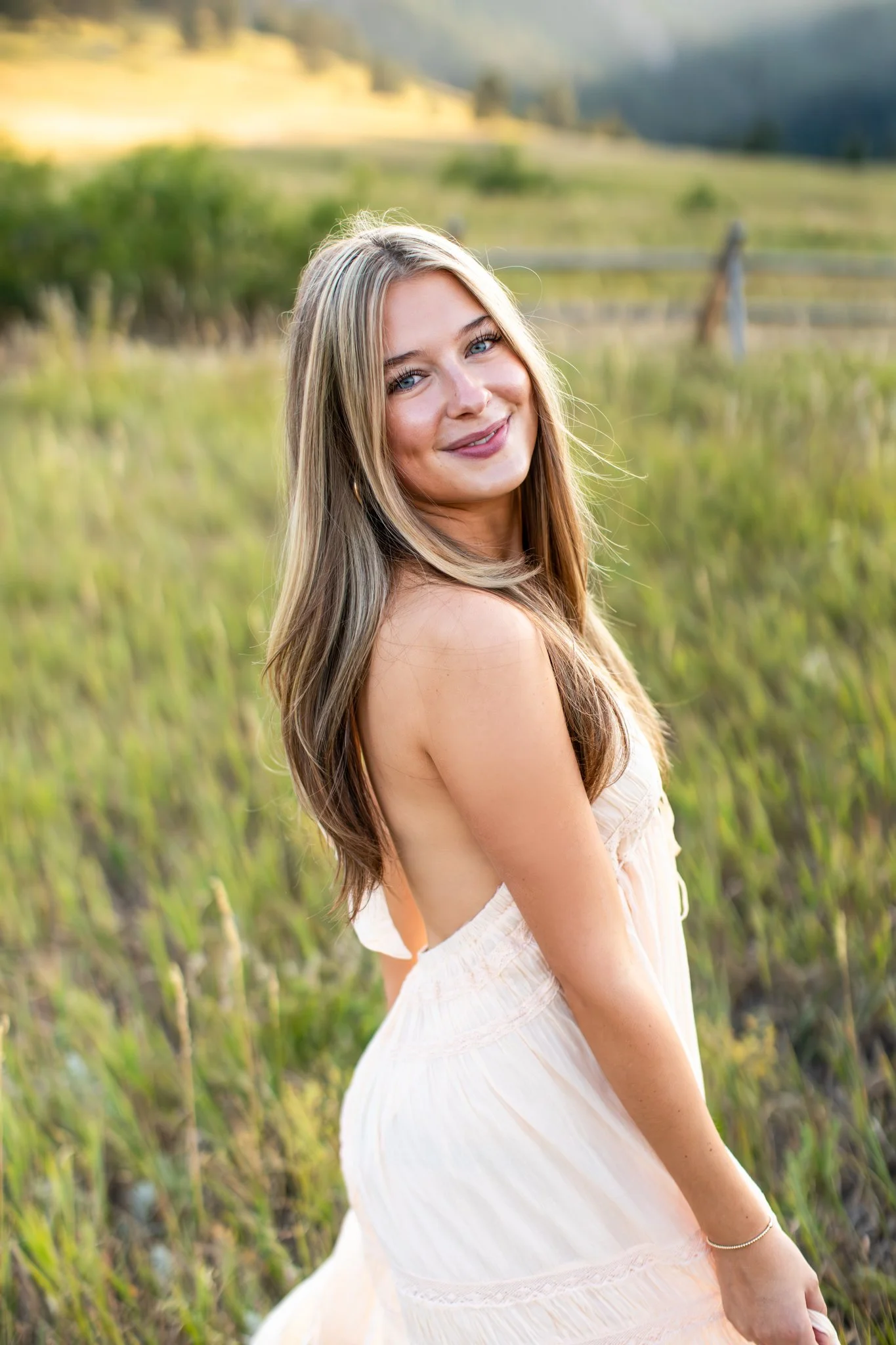 Portrait of high school girl in flowing maxi dress in a field.