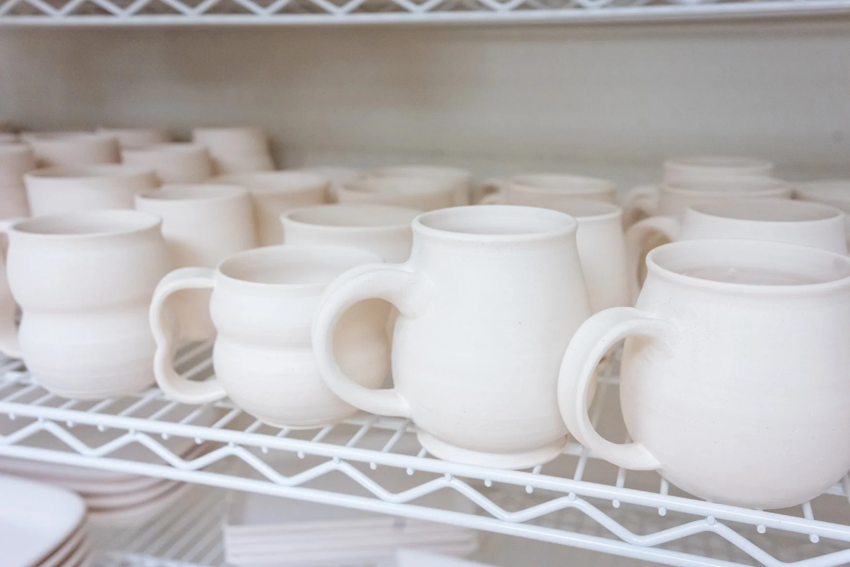 Paint-Your-Own-Pottery mugs on a shelf