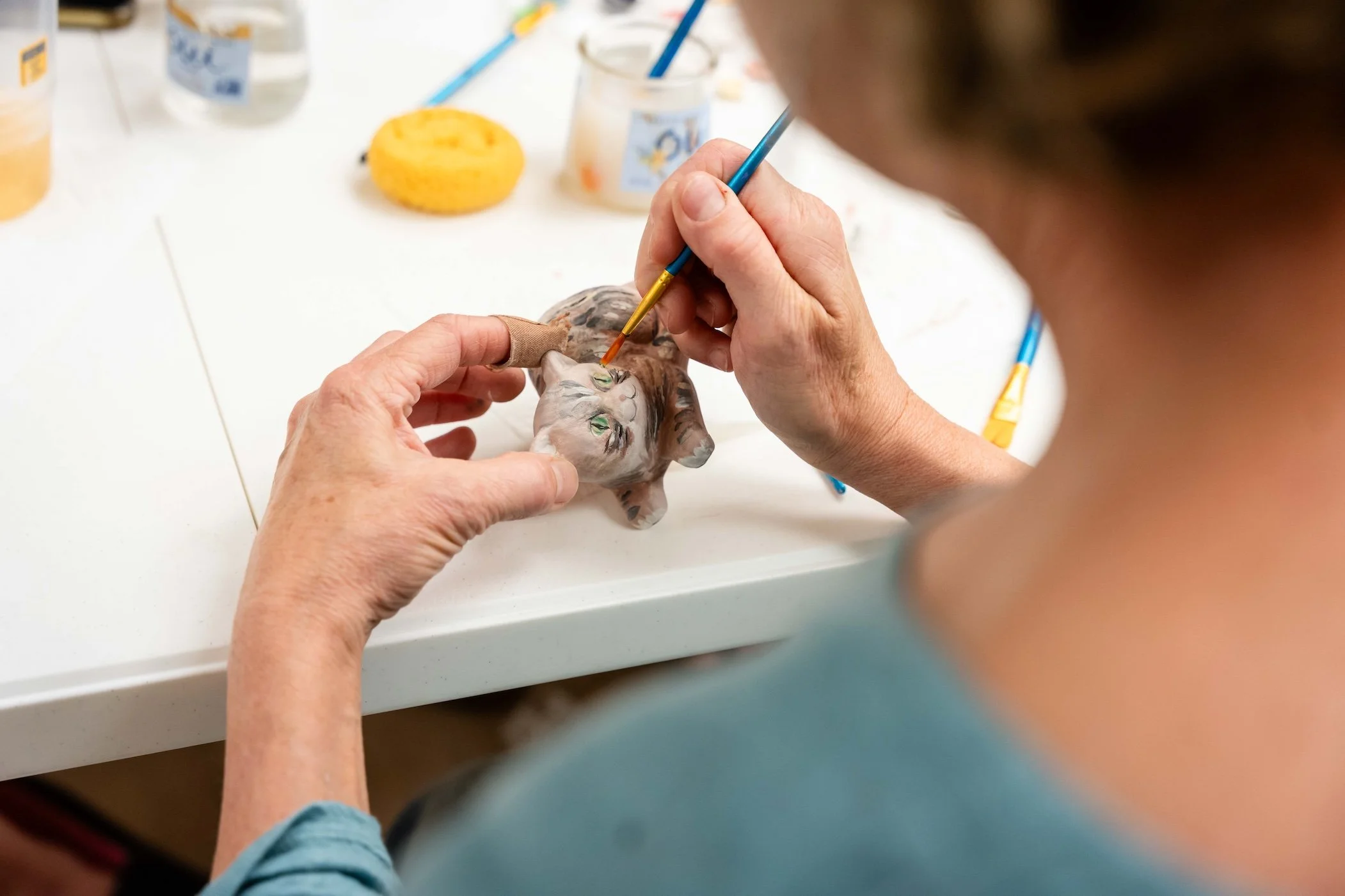 A Clayground member paints a piece of pottery