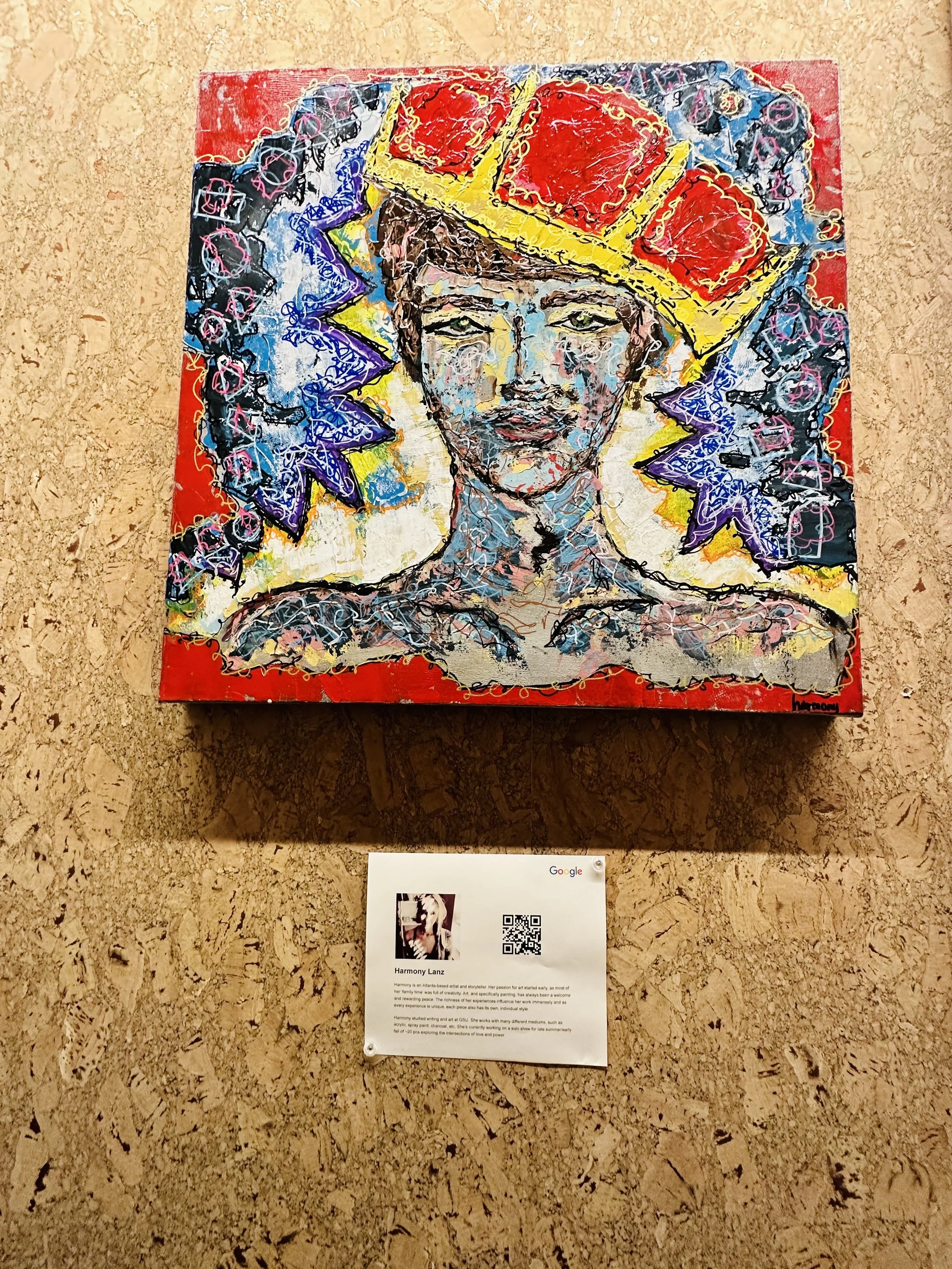 Colorful mixed-media artwork of a woman with an elaborate headdress, featuring bold colors and abstract patterns, mounted on a corkboard wall.