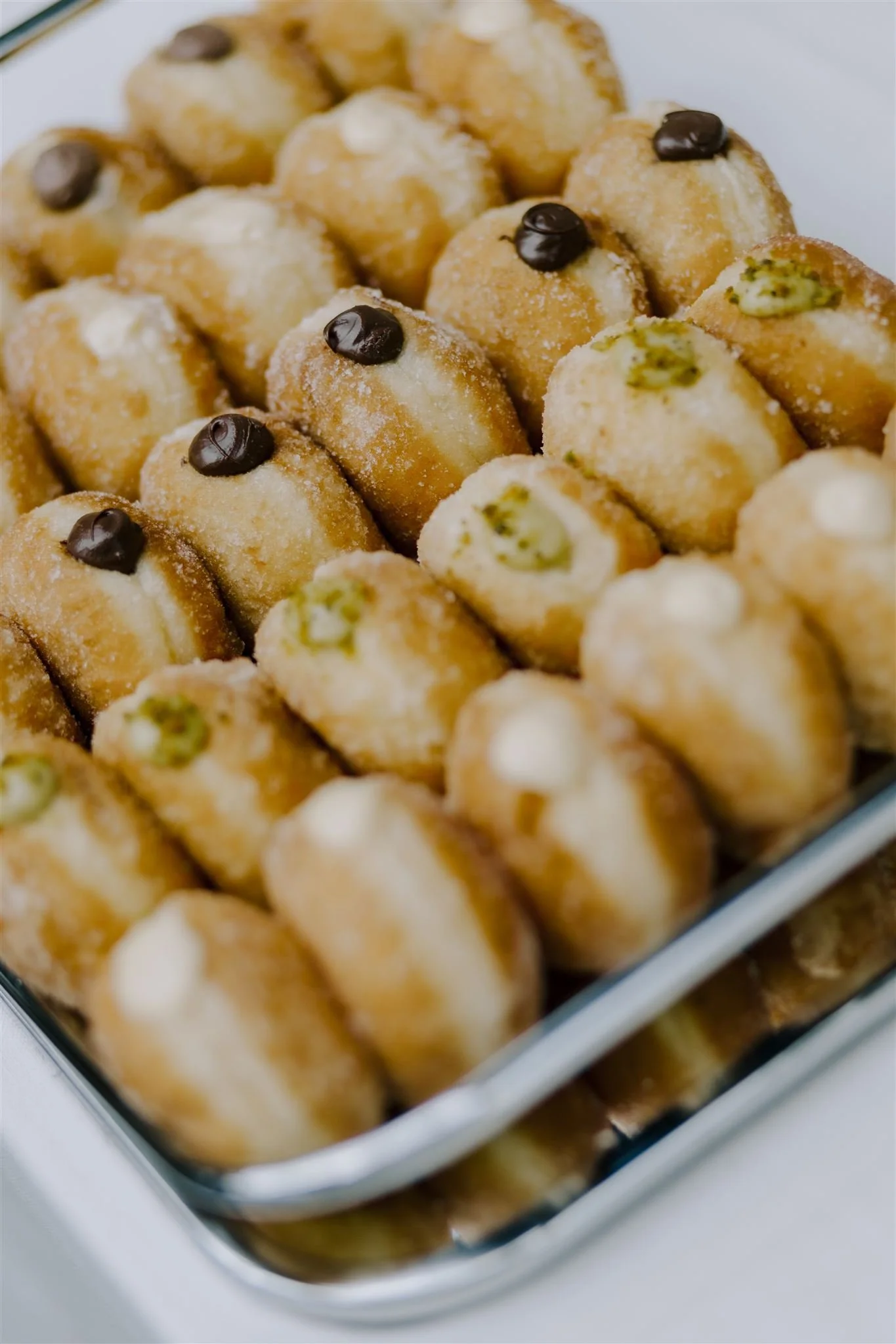 Tray of assorted mini donuts with chocolate and pistachio toppings.