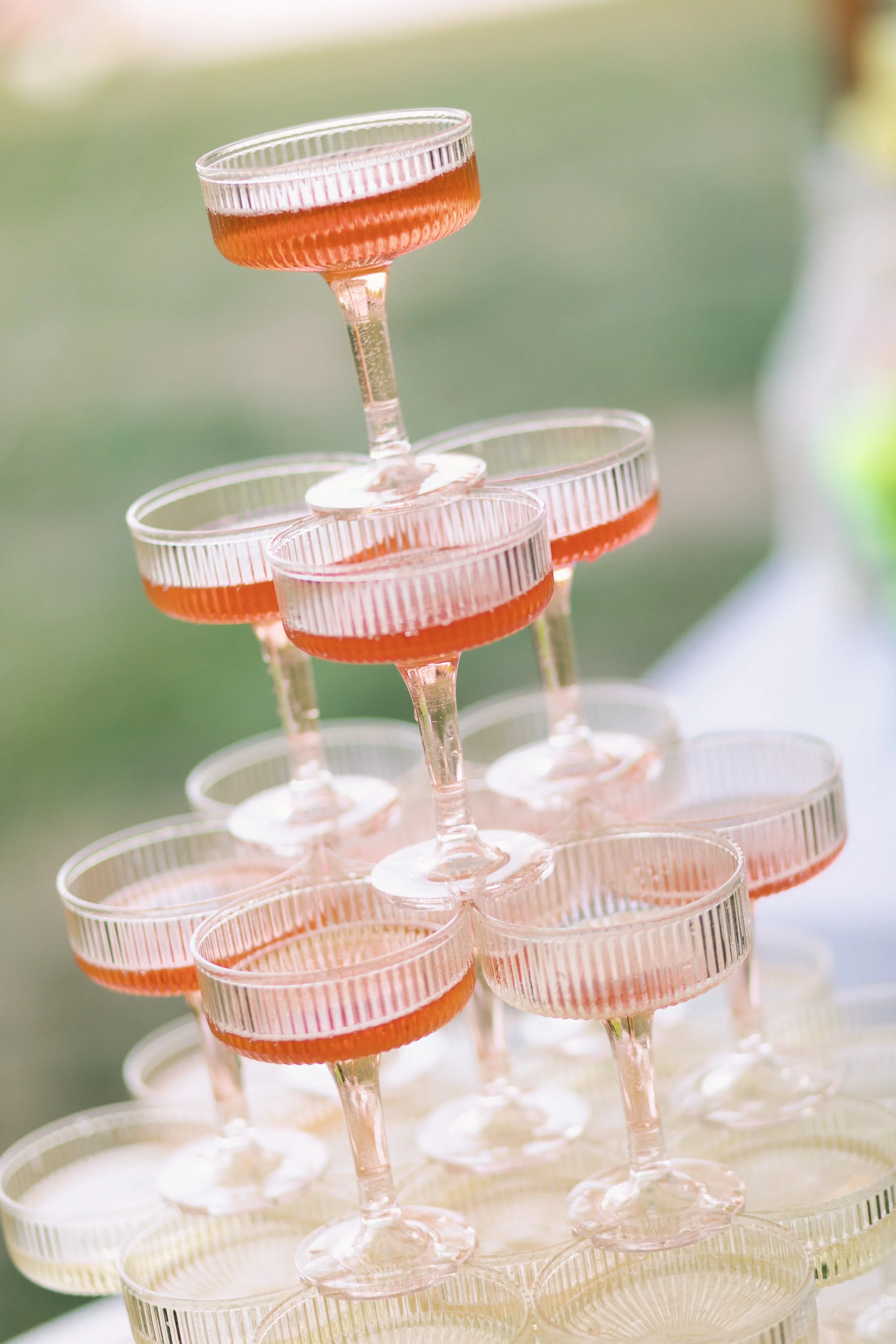Stacked pink cocktail glasses with a tiered arrangement of drinks.