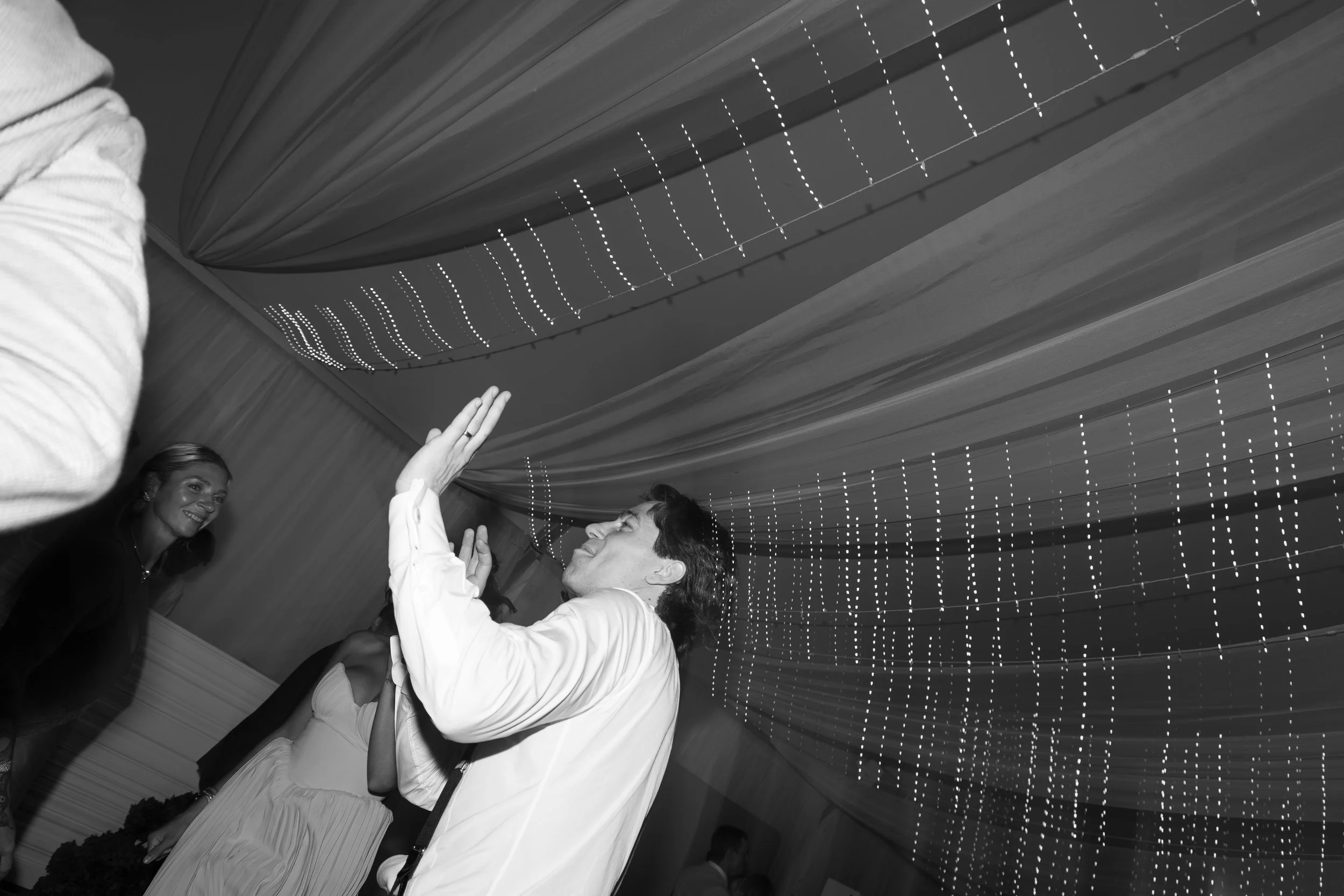 People dancing and socializing indoors under hanging lights during an event.