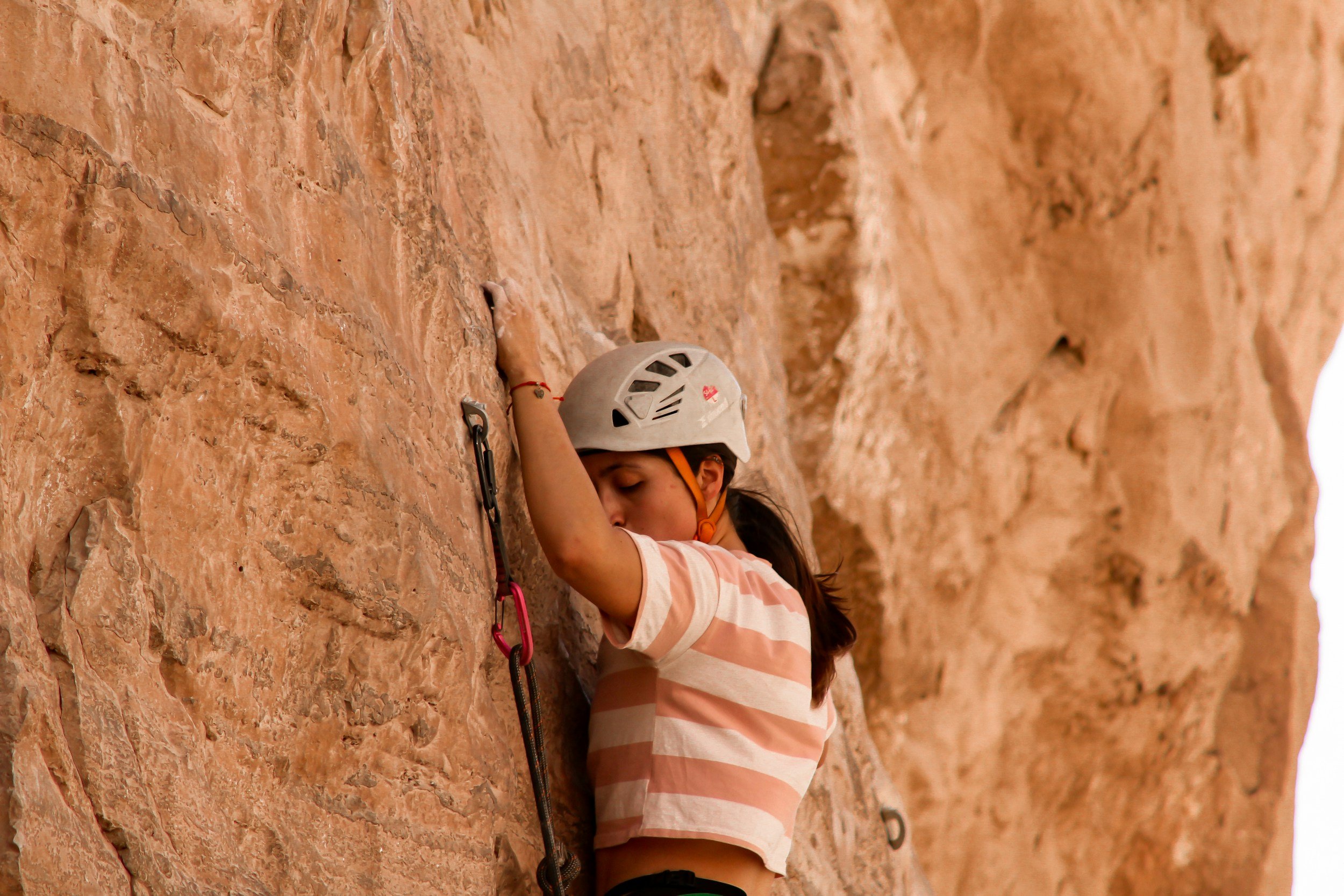 Climber even with a bolt sport climbing on sandstone
