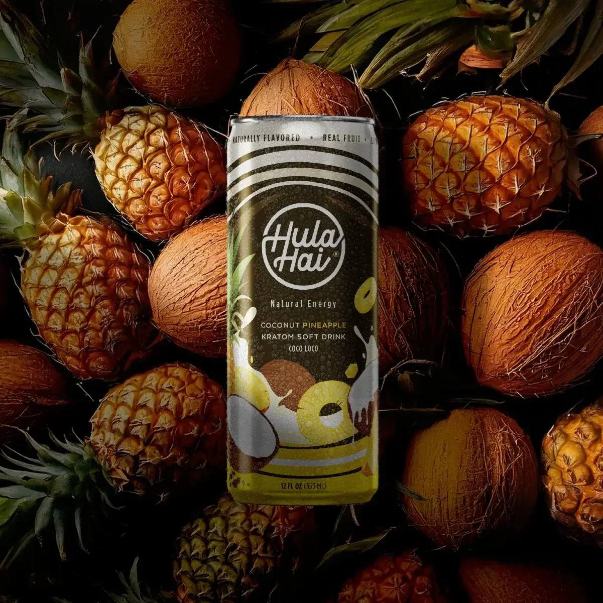 A can of Hula Hai Coconut Pineapple Kratom Soft Drink standing upright among pineapples and coconuts.