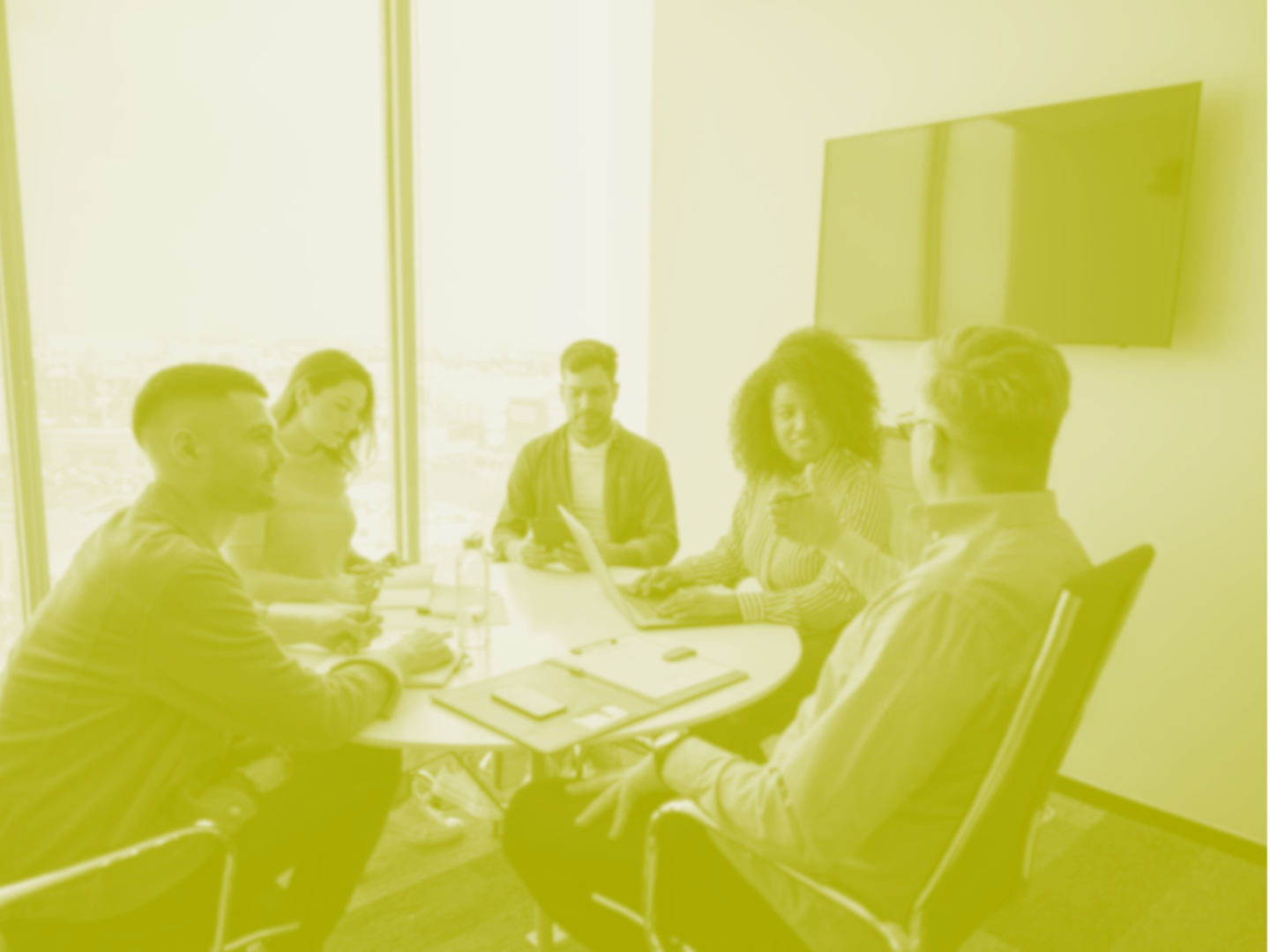 A blurred image of a group of five people sitting around a table in a conference room.