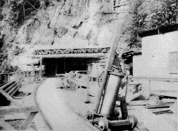 black and white historical photo of a mine entrance into a cliffside, path leading to a dark rectangular opening 