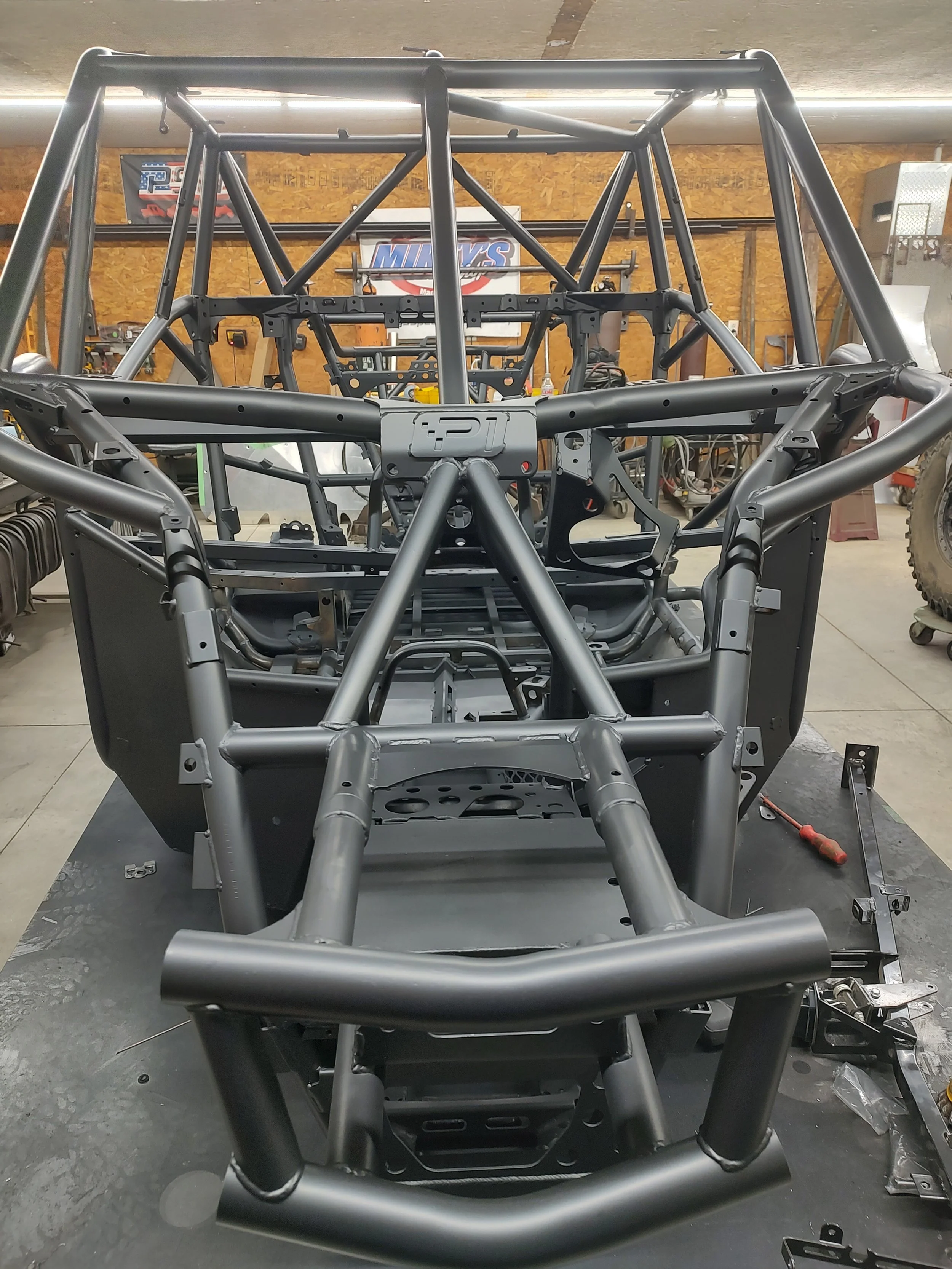 A metal frame structure of a race car inside a workshop.