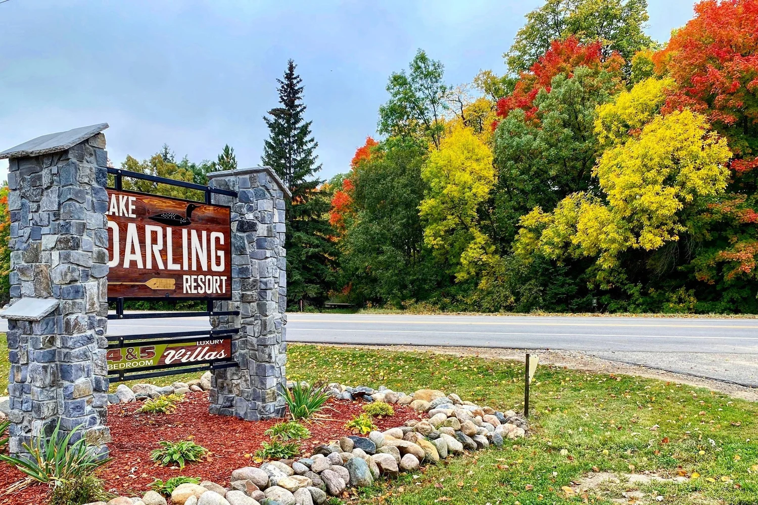 The Lake Darling Resort entrance sign with a bank of red, orange and yellow trees behind it