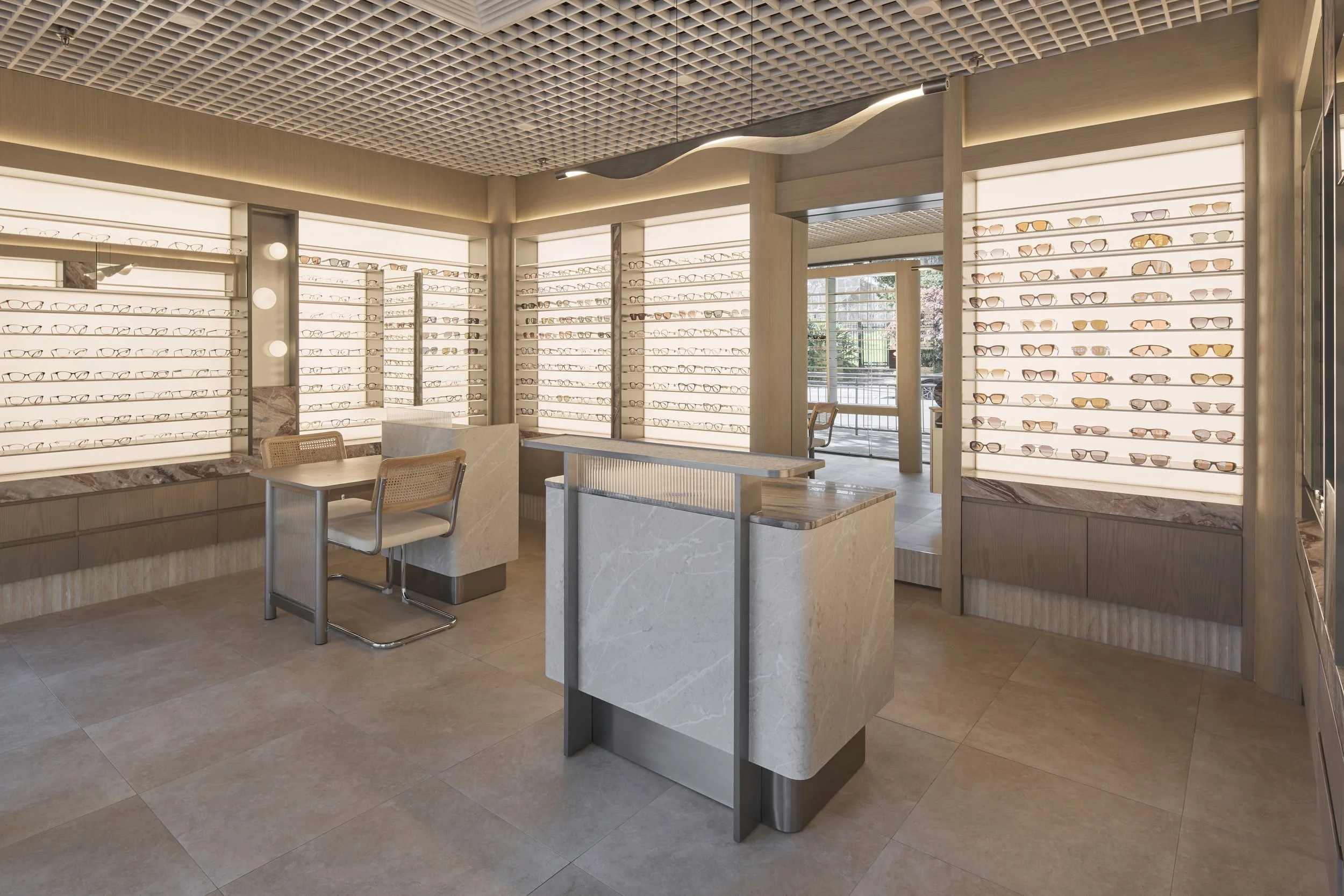 Bright Eyes Optics Mona Vale commercial retail fit-out featuring illuminated eyewear displays, custom stone counters, timber joinery, feature grid ceiling and integrated LED lighting – Sydney City Renovations.