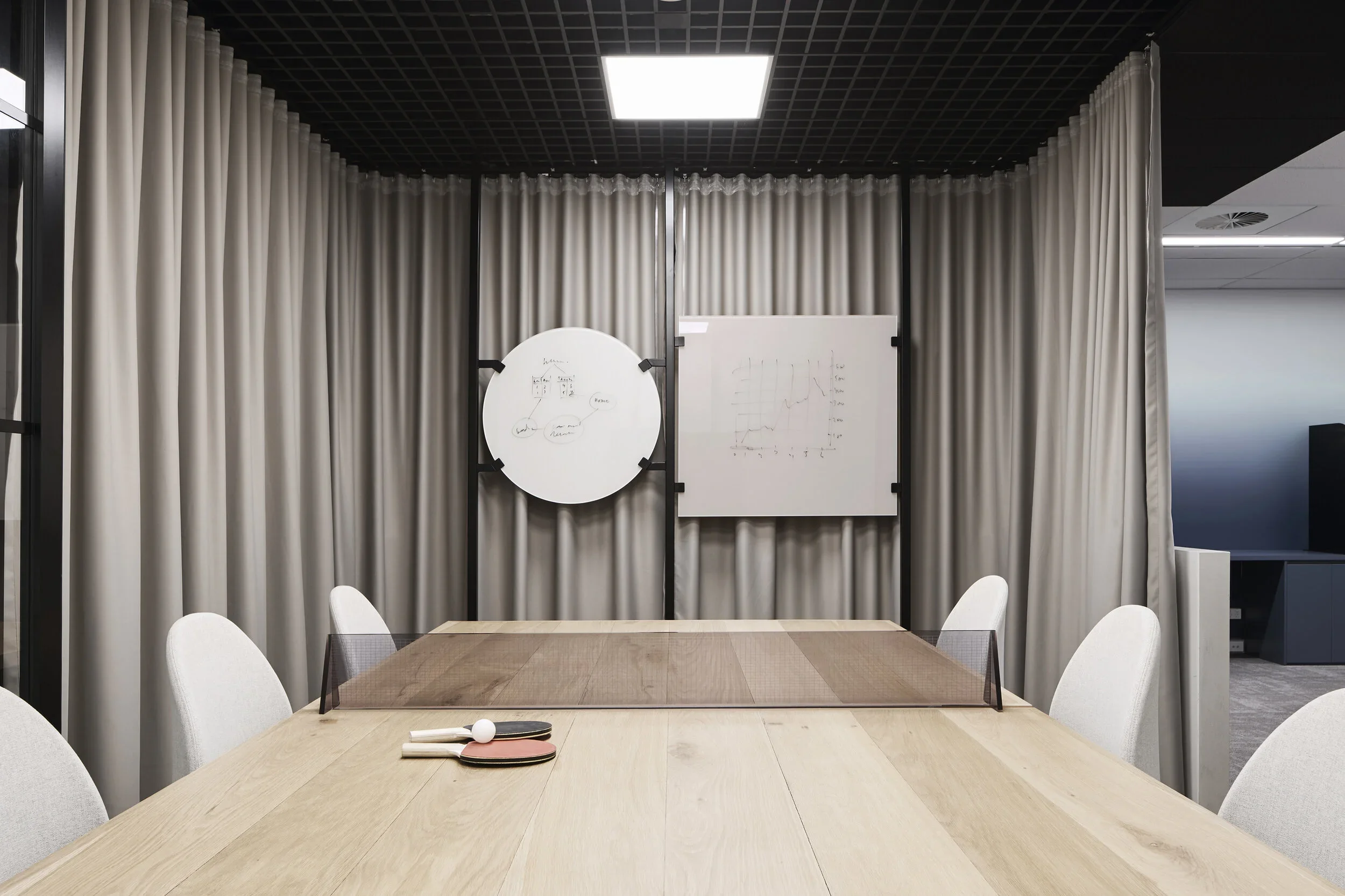 SDP Solutions Sydney CBD commercial office fit-out featuring a contemporary meeting room with custom timber conference table, acoustic curtains, black grid ceiling, integrated lighting and flexible collaborative workspace – Sydney City Renovations.