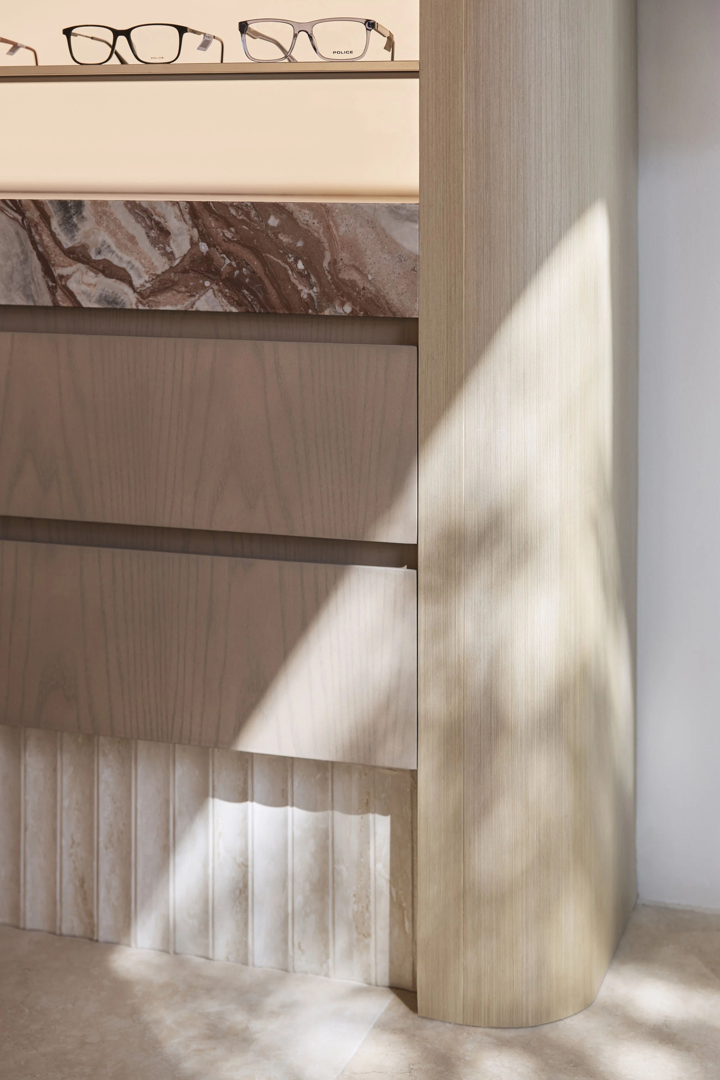 Bright Eyes Optics retail fit-out in Mona Vale, Sydney, showcasing detailed custom joinery, curved timber finishes, natural stone accents and textured wall tiles – Sydney City Renovations, commercial fit-out specialists.