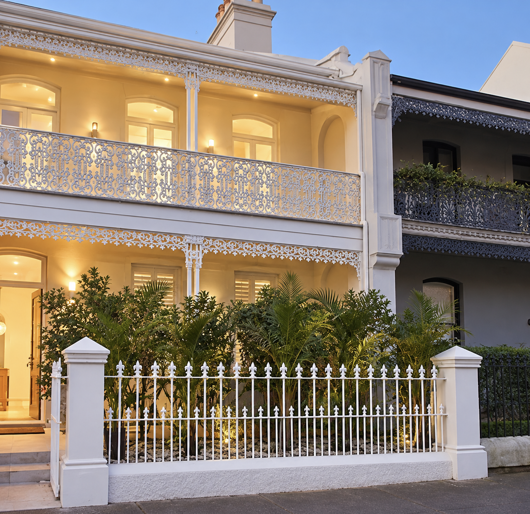 Sydney City Renovations heritage terrace house renovation in Sydney, featuring a beautifully restored Victorian-style façade, ornate wrought-iron balconies, decorative lacework, elegant exterior lighting, landscaped front garden.