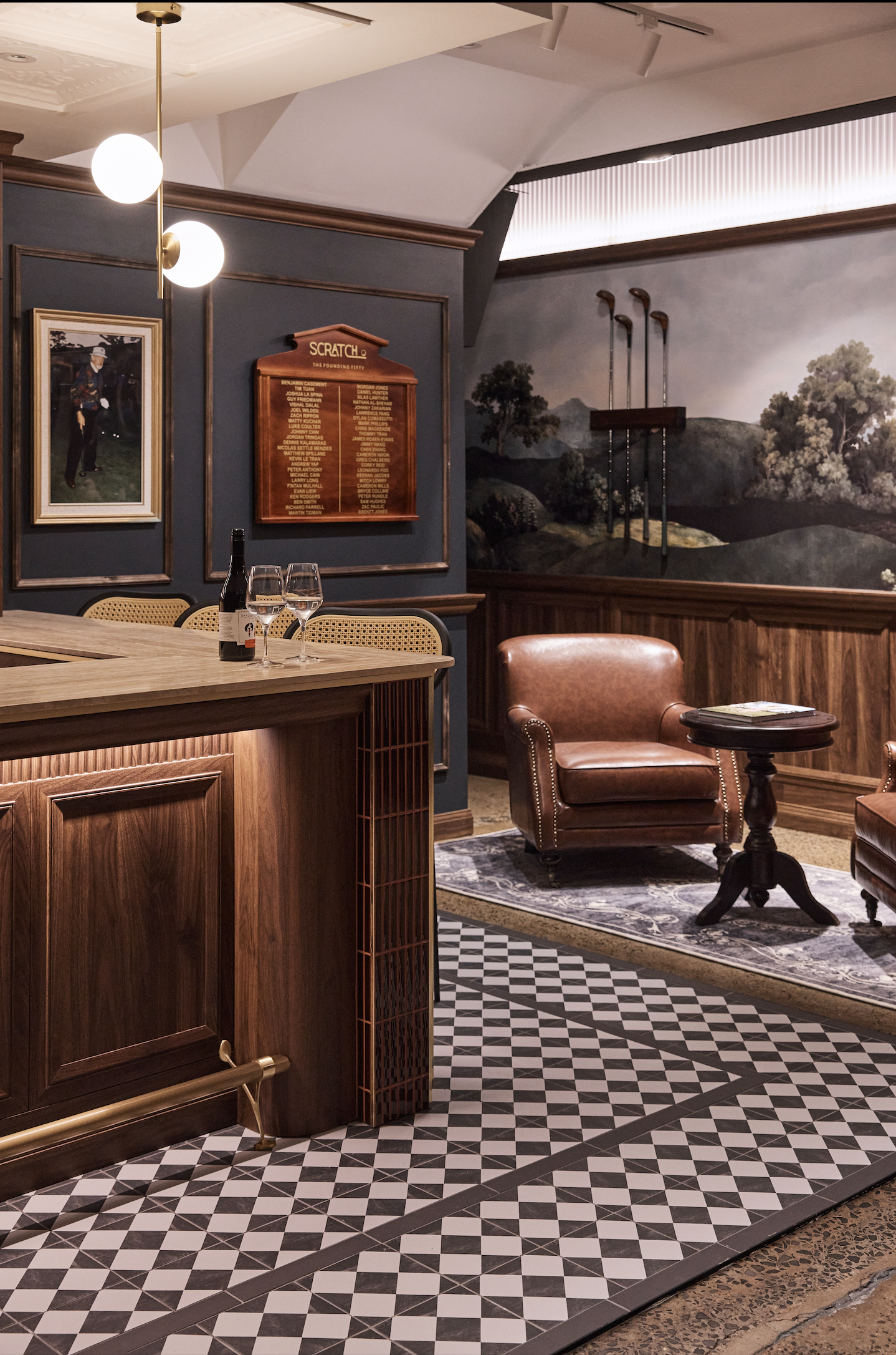 Scratch Golf Studio Marrickville commercial fit-out featuring custom timber bar joinery, decorative wall mouldings, vintage leather lounge seating, geometric floor tiles, brass lighting and golf-inspired feature artwork – Sydney City Renovations.