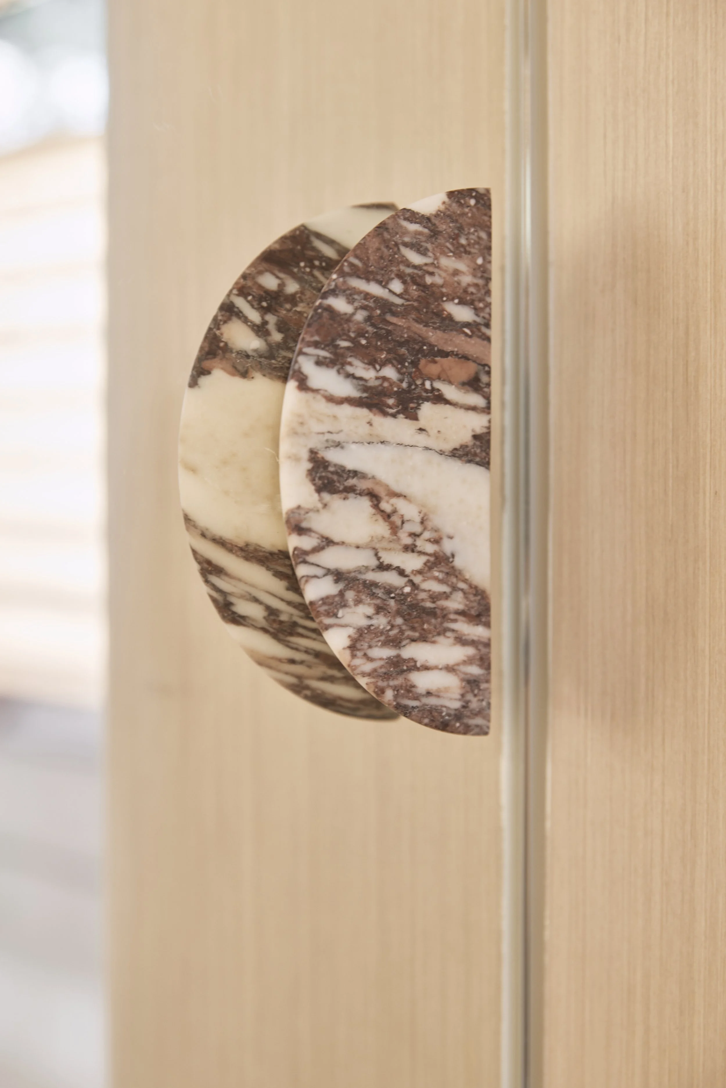 Custom-made marble door handles featuring sculptural detailing and rich natural stone veining, paired with warm timber joinery in a luxury Sydney retail fit-out – Sydney City Renovations.