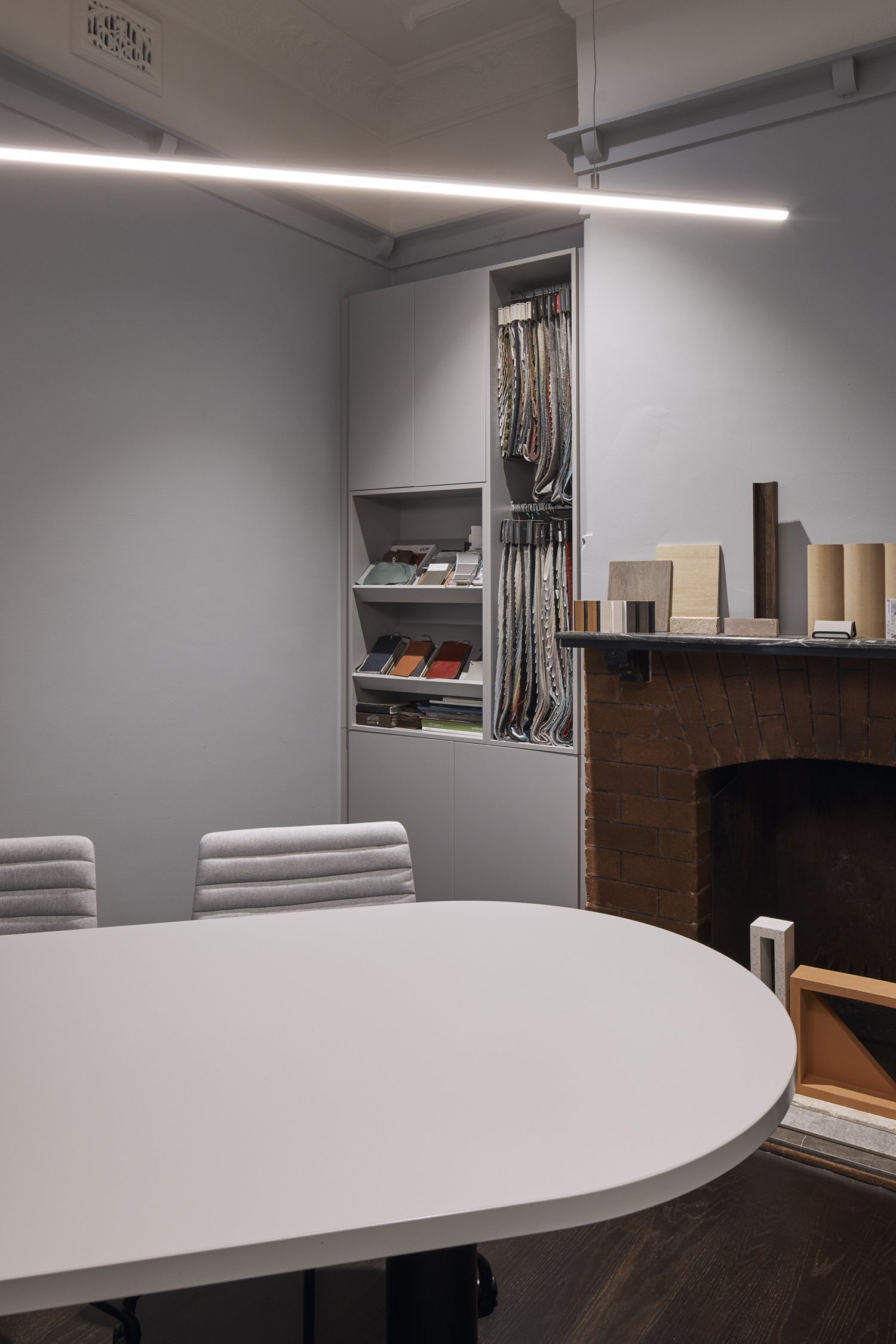 Sydney City Renovations home office renovation featuring a contemporary meeting table, custom built-in cabinetry, organised material sample storage, modern linear pendant lighting and preserved heritage details, including decorative cornices.