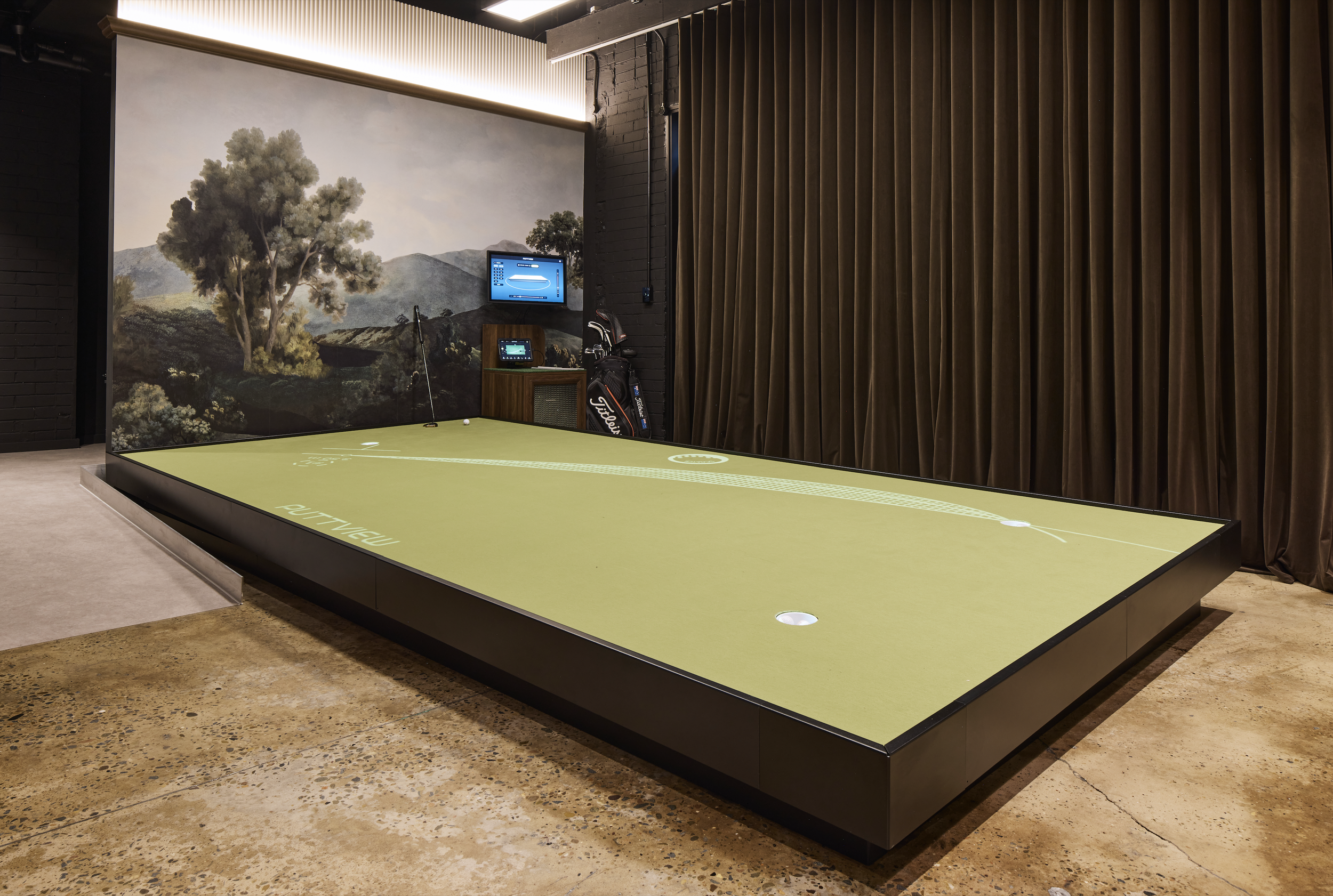 Scratch Golf Studio Marrickville commercial fit-out featuring an indoor golf putting simulator, custom raised putting green, golf-inspired landscape mural, polished concrete flooring, dark curtains and integrated lighting – Sydney City Renovations. 
