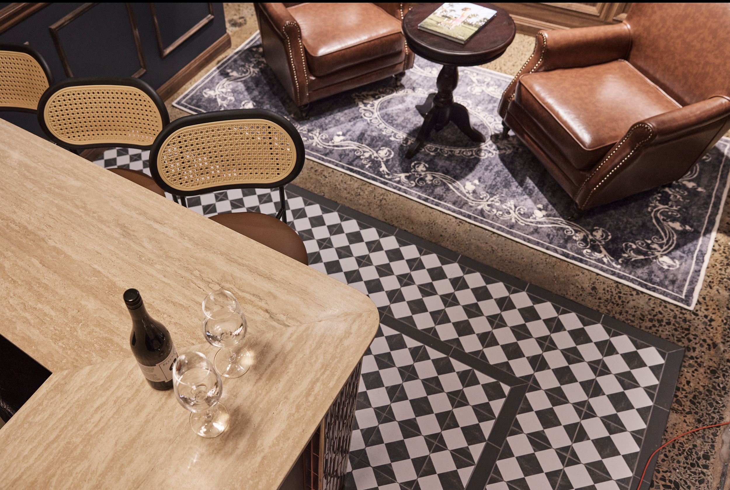 Sydney City Renovations commercial hospitality fit-out featuring rich timber wall panelling, vintage leather armchairs, decorative geometric floor tiles, natural stone benchtops and custom joinery, creating a sophisticated timeless character.