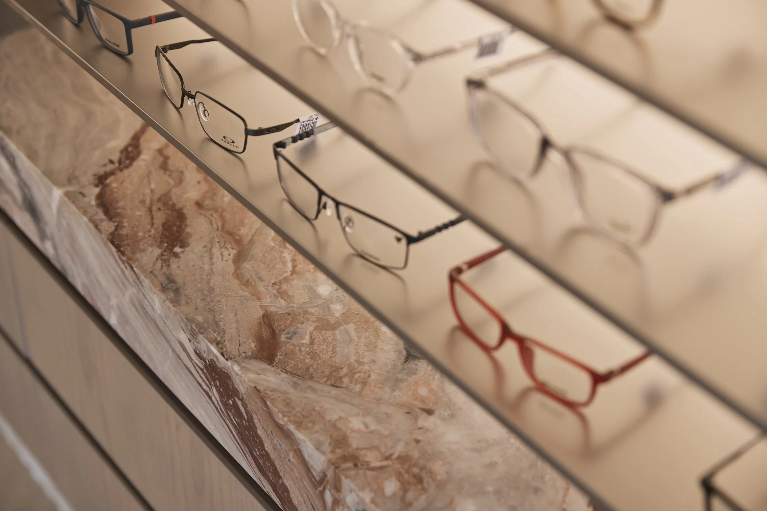 Bright Eyes Optics retail fit-out in Mona Vale, Sydney, showcasing detailed eyewear displays, polished stone finishes, custom timber joinery and refined shelving details – Sydney City Renovations, commercial fit-out specialists.