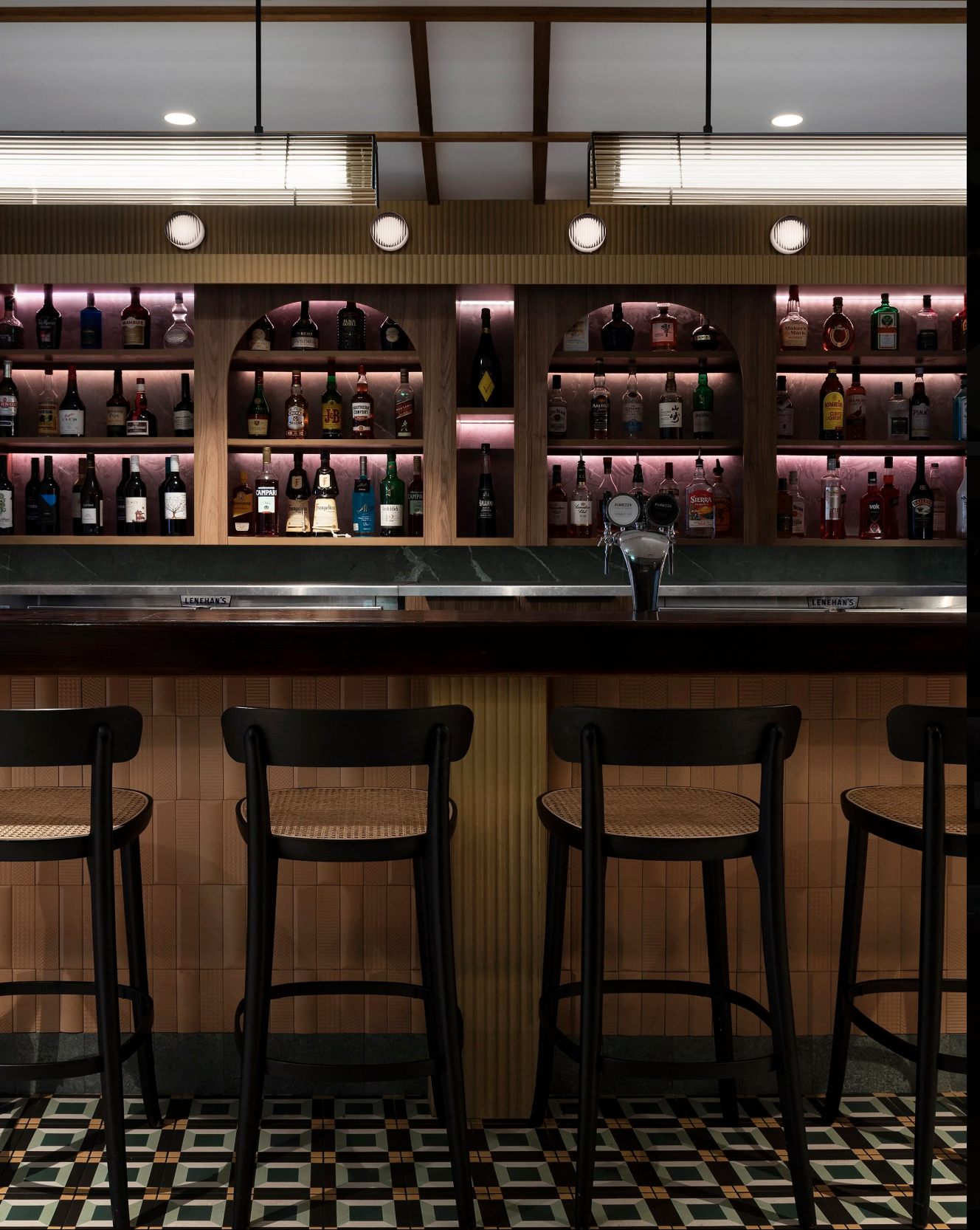 Rios Restaurant Parramatta commercial fit-out featuring custom timber bar joinery, arched display shelving, backlit liquor displays, decorative tiled bar front, patterned flooring and contemporary pendant lighting – Sydney City Renovations.