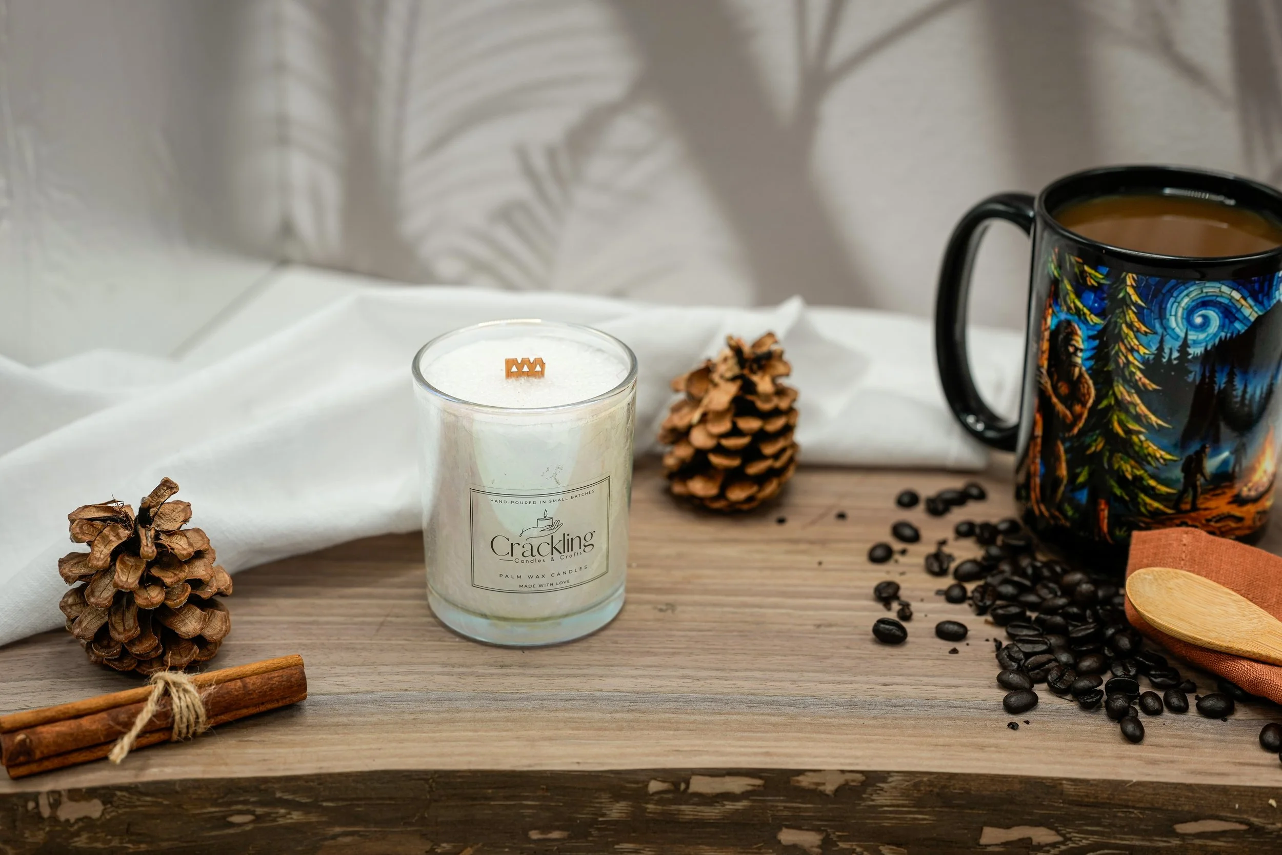 Coffee palm wax candle with a wooden wick, black illustrated mug, coffee beans, and cinnamon sticks