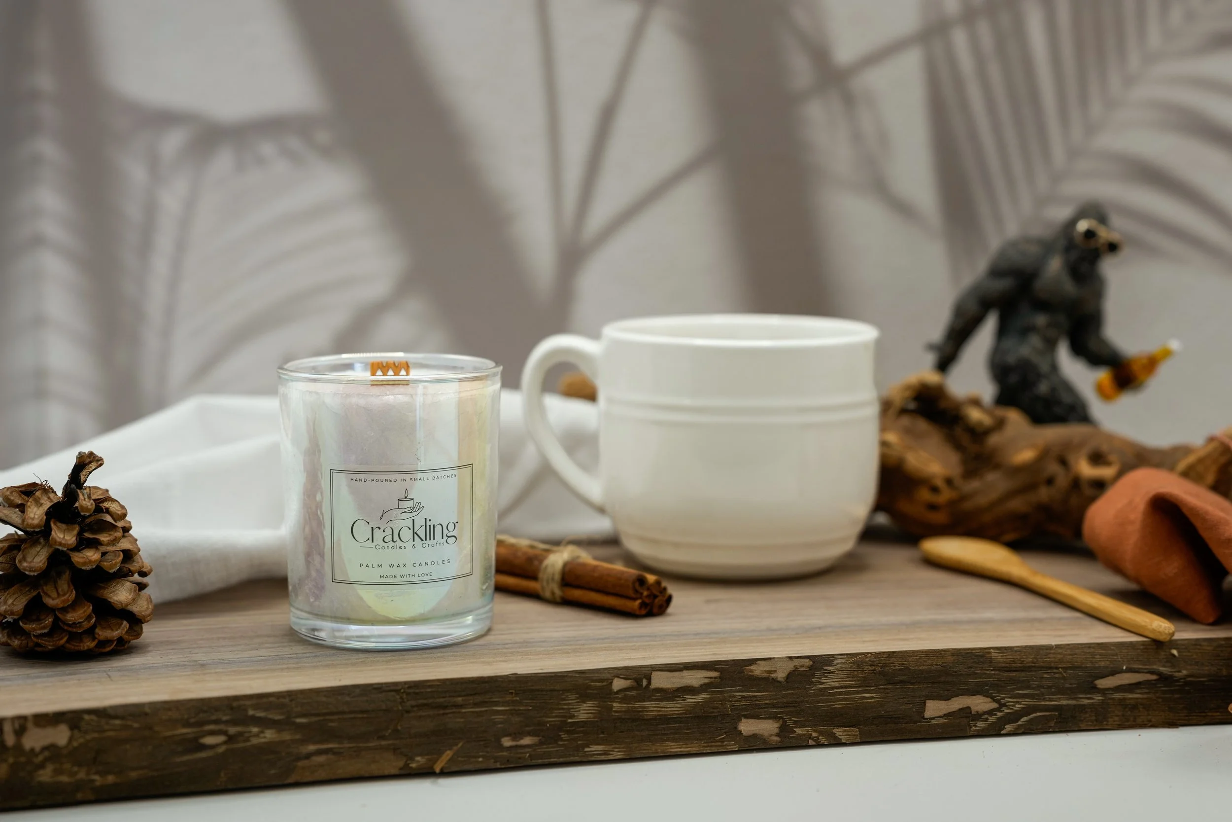 Coffee scented palm wax candle with wooden wick styled with a white coffee cup, cinnamon sticks, and coffee beans.