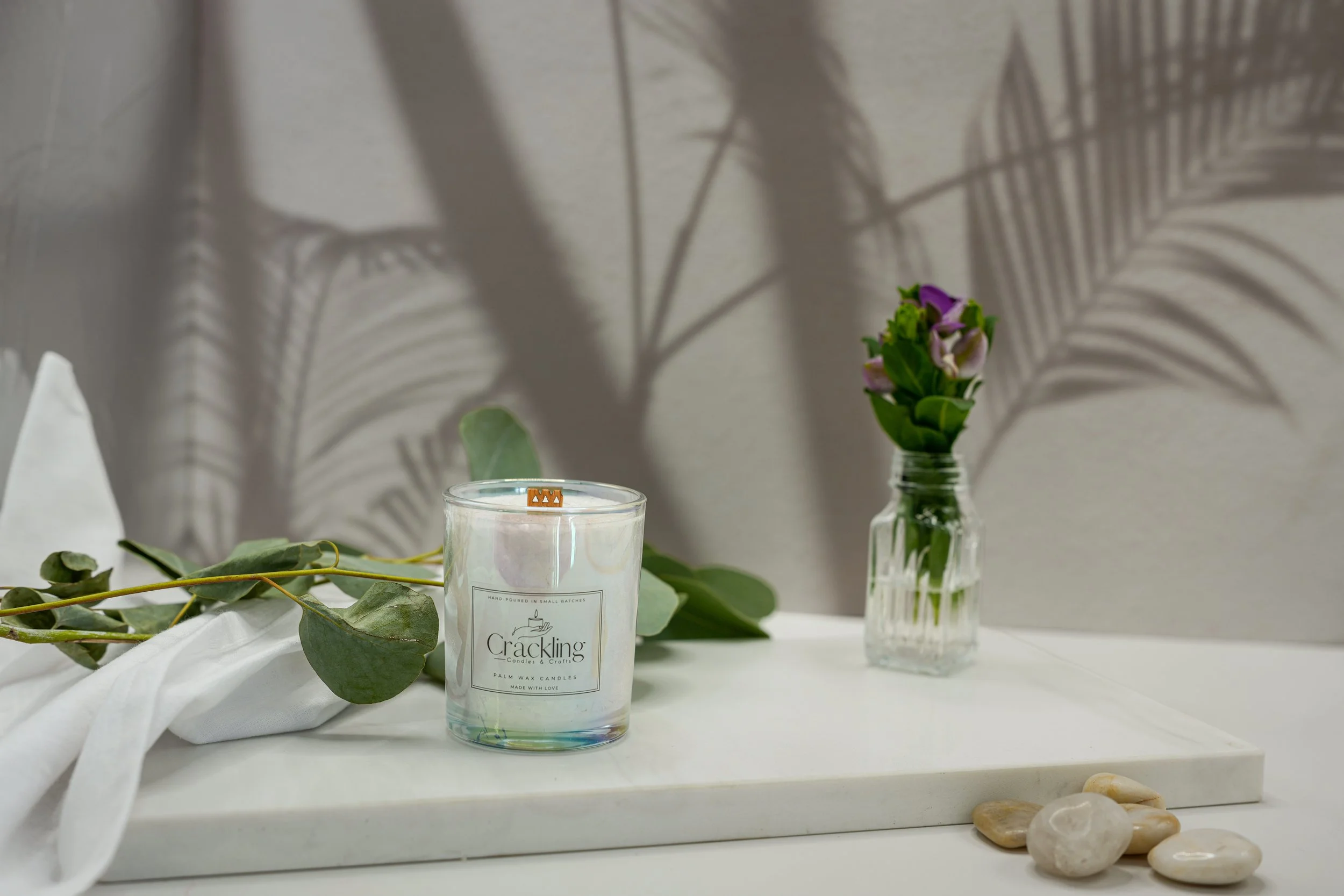 6 oz Sweet Pea palm wax candle with a wooden wick, styled with eucalyptus and delicate purple flowers in a soft spa-inspired setting.