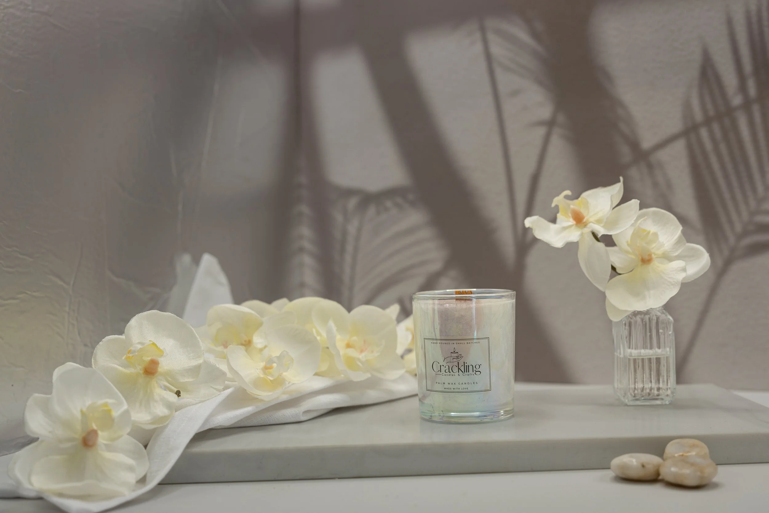 Gardenia Bouquet candle in a glass jar beside white flowers on a light display surface.
