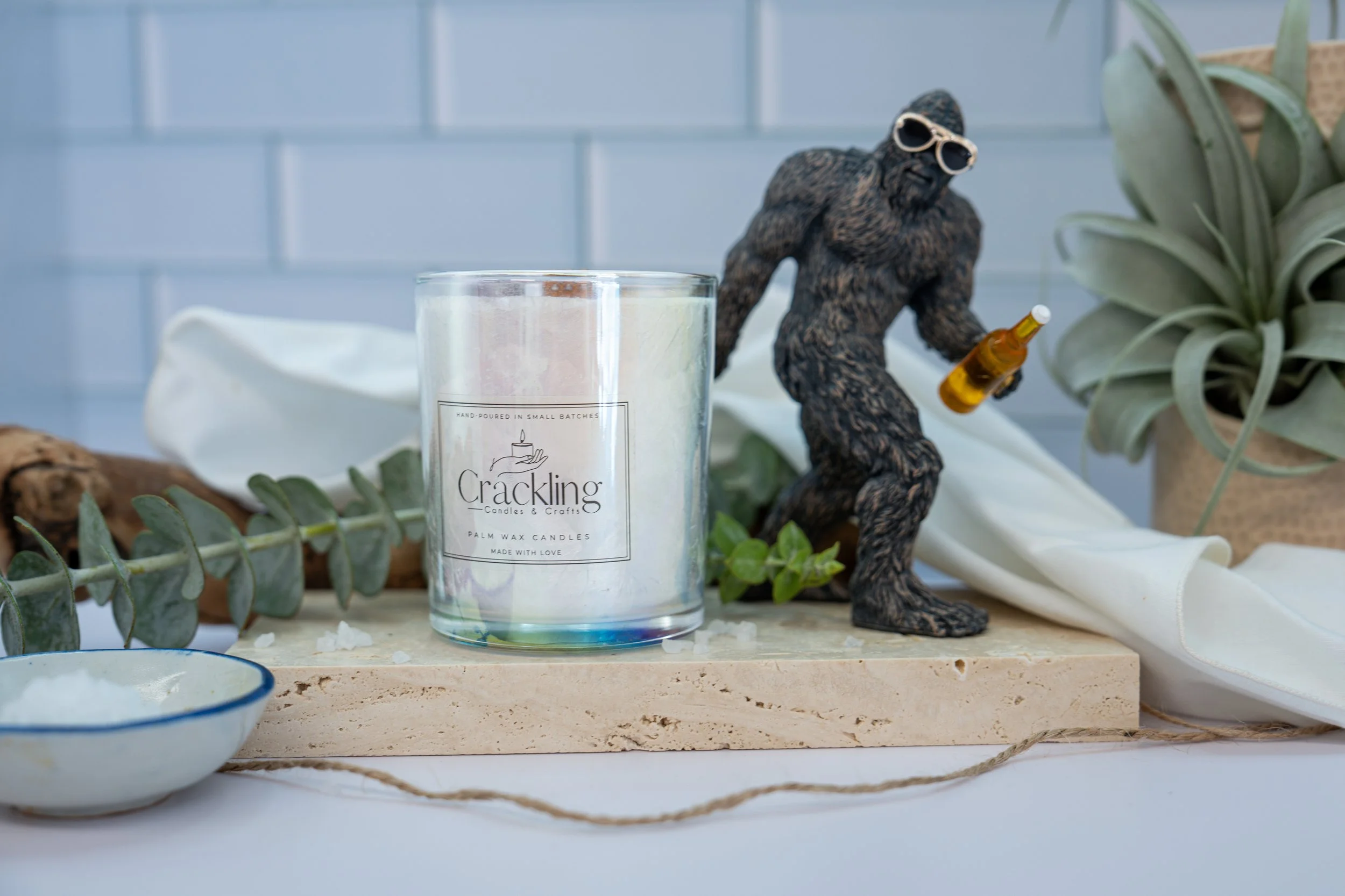 6 oz White Sage & Sea Salt candle with a wooden wick, styled on a light wood board