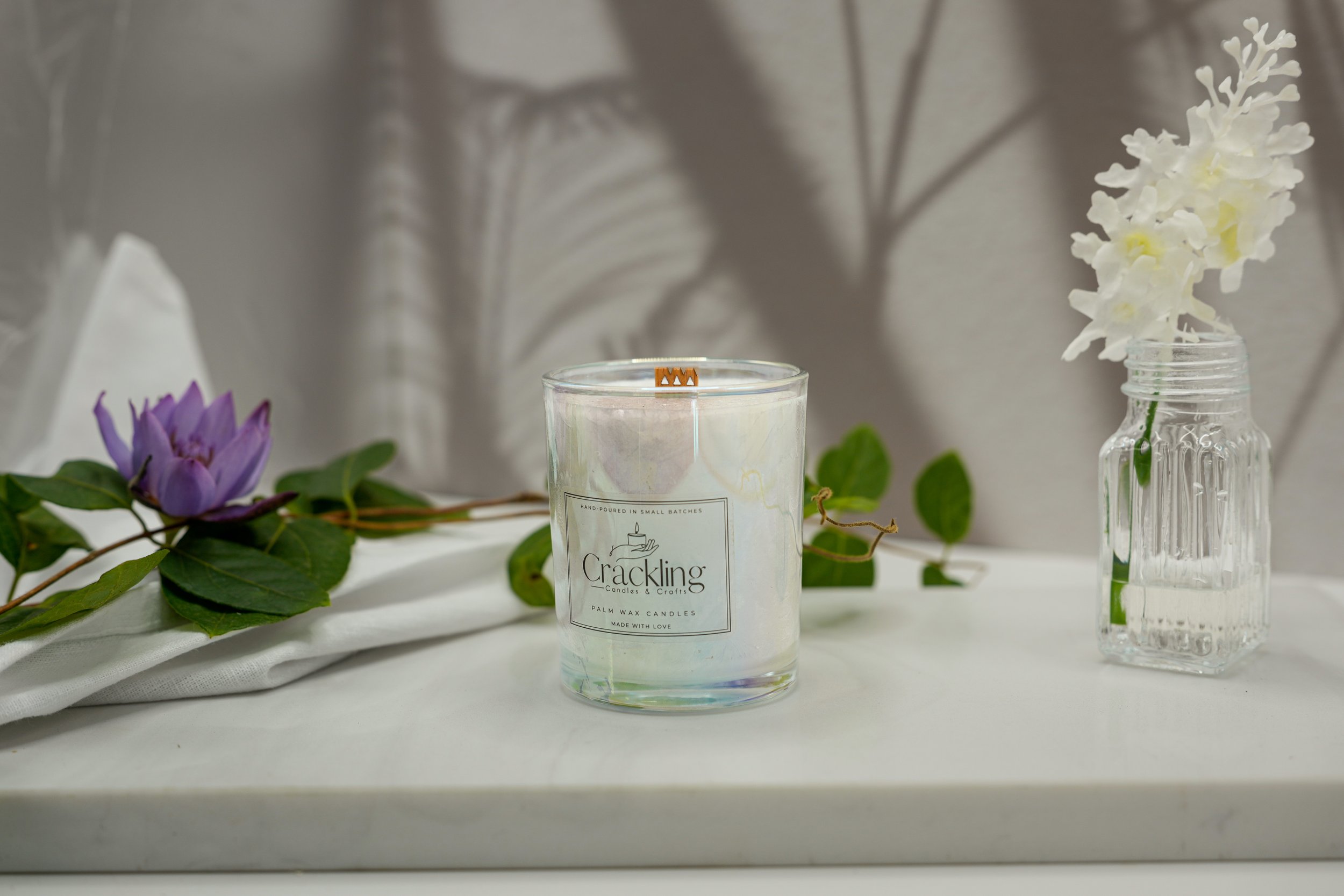 Water Lily & Jasmine candle displayed with a purple flower and greenery