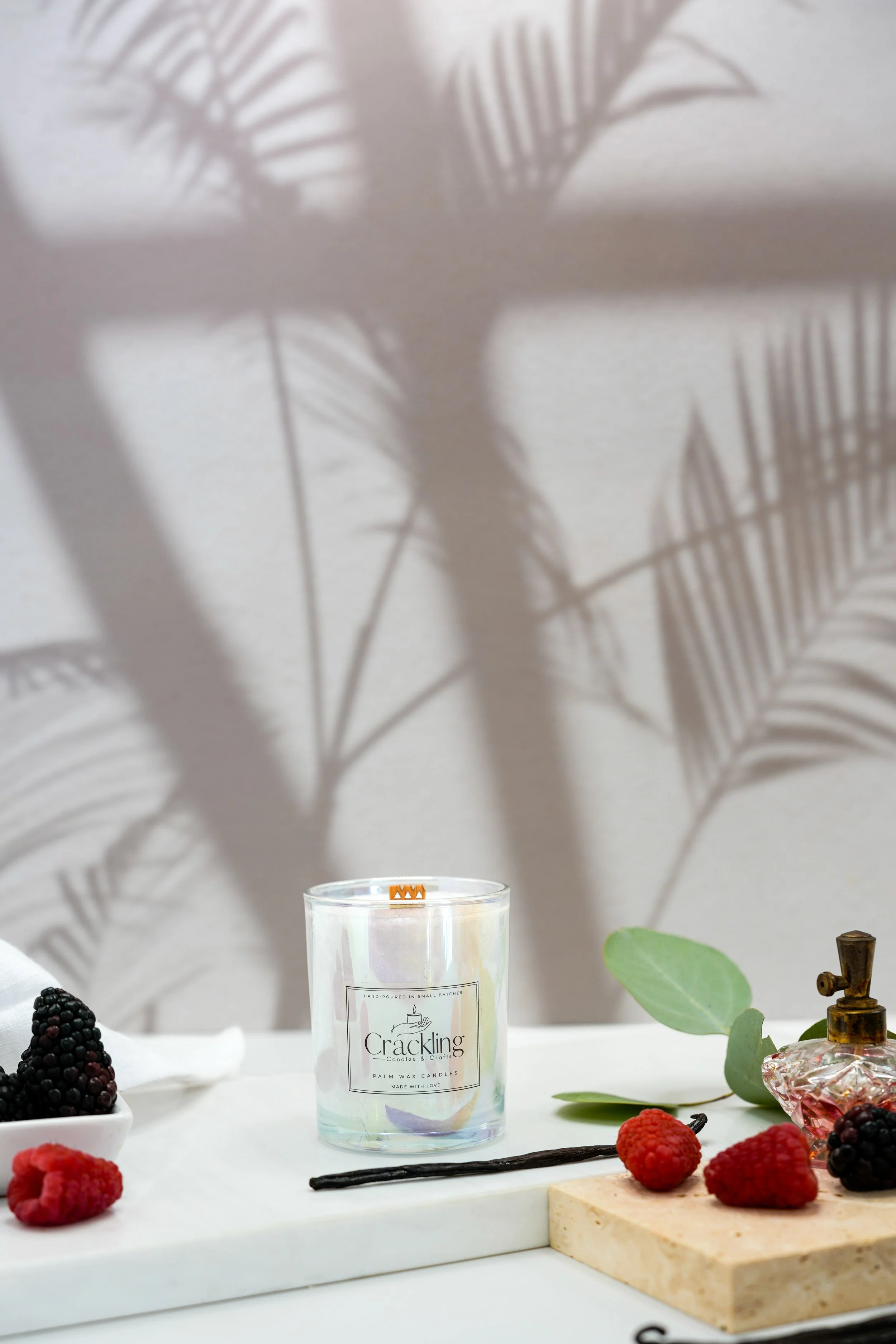 Black Raspberry & Vanilla candle displayed with fresh berries, vanilla beans, eucalyptus leaves, and soft neutral linen.
