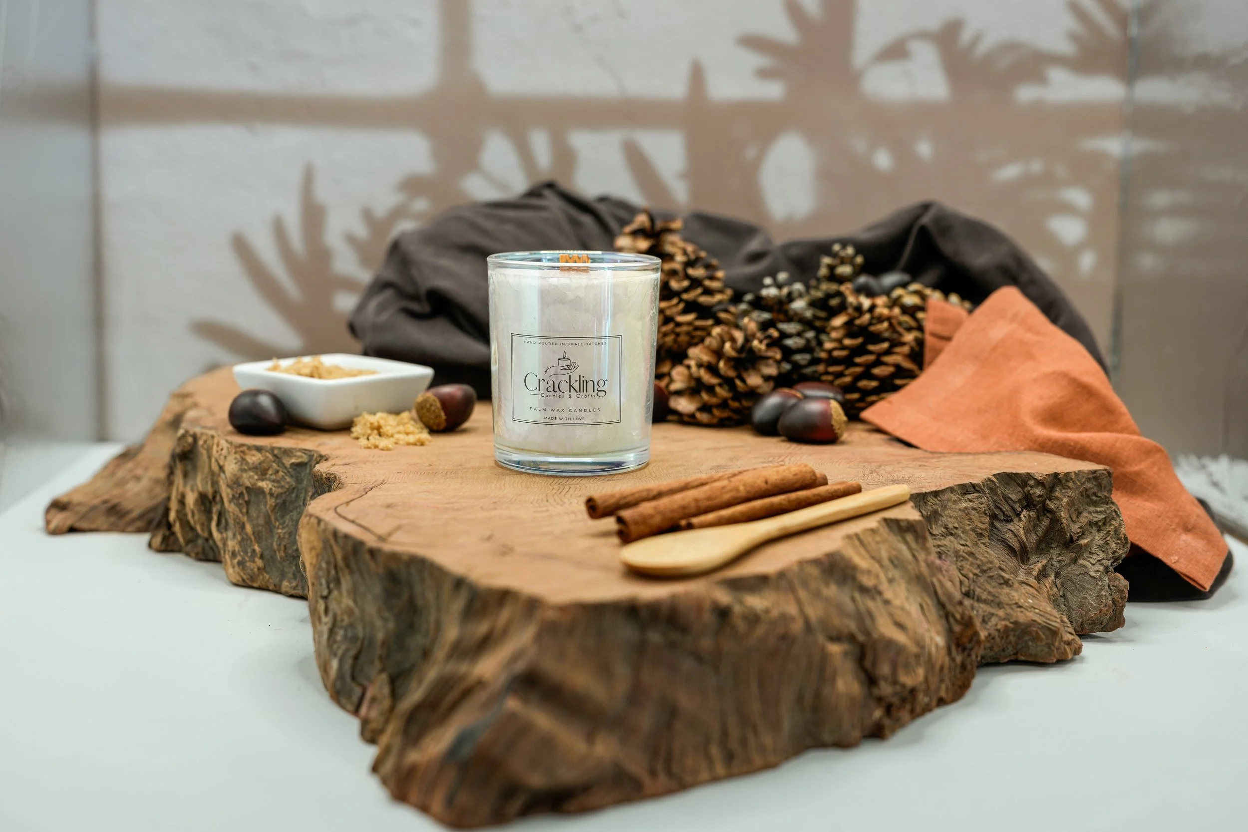 6 oz Chestnuts & Brown Sugar palm wax candle with a wooden wick, styled on natural wood with pinecones, cinnamon sticks, and warm fall accents.
